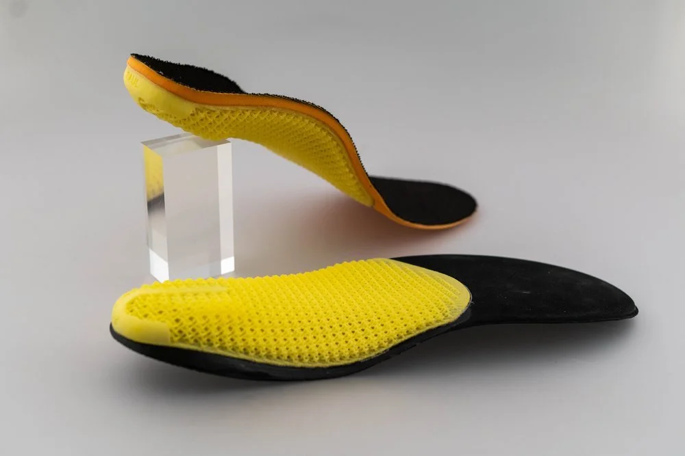 Soft Shoe inner in yellow displayed by glass supports taken by Nick Matthews who offers a product photography service