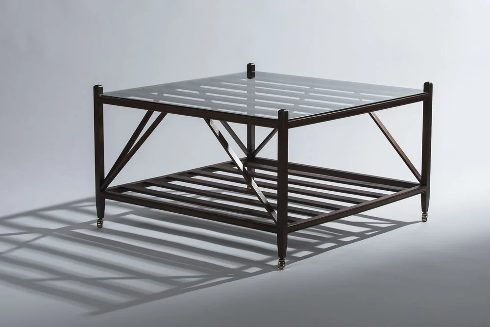 A wooden and glass coffee table with a lower shelf, casting shadows on a plain light background.