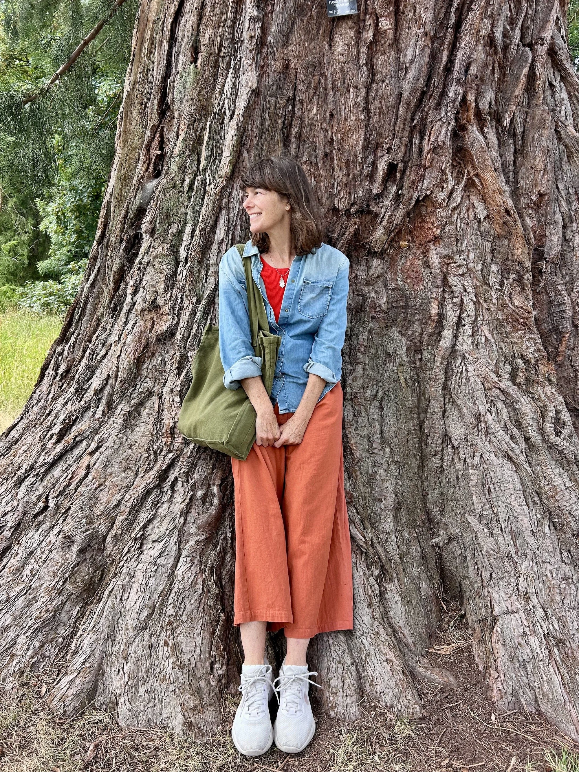 Delyth Johnson, midlife awakening practitioner, standing in woodland in the Lake District