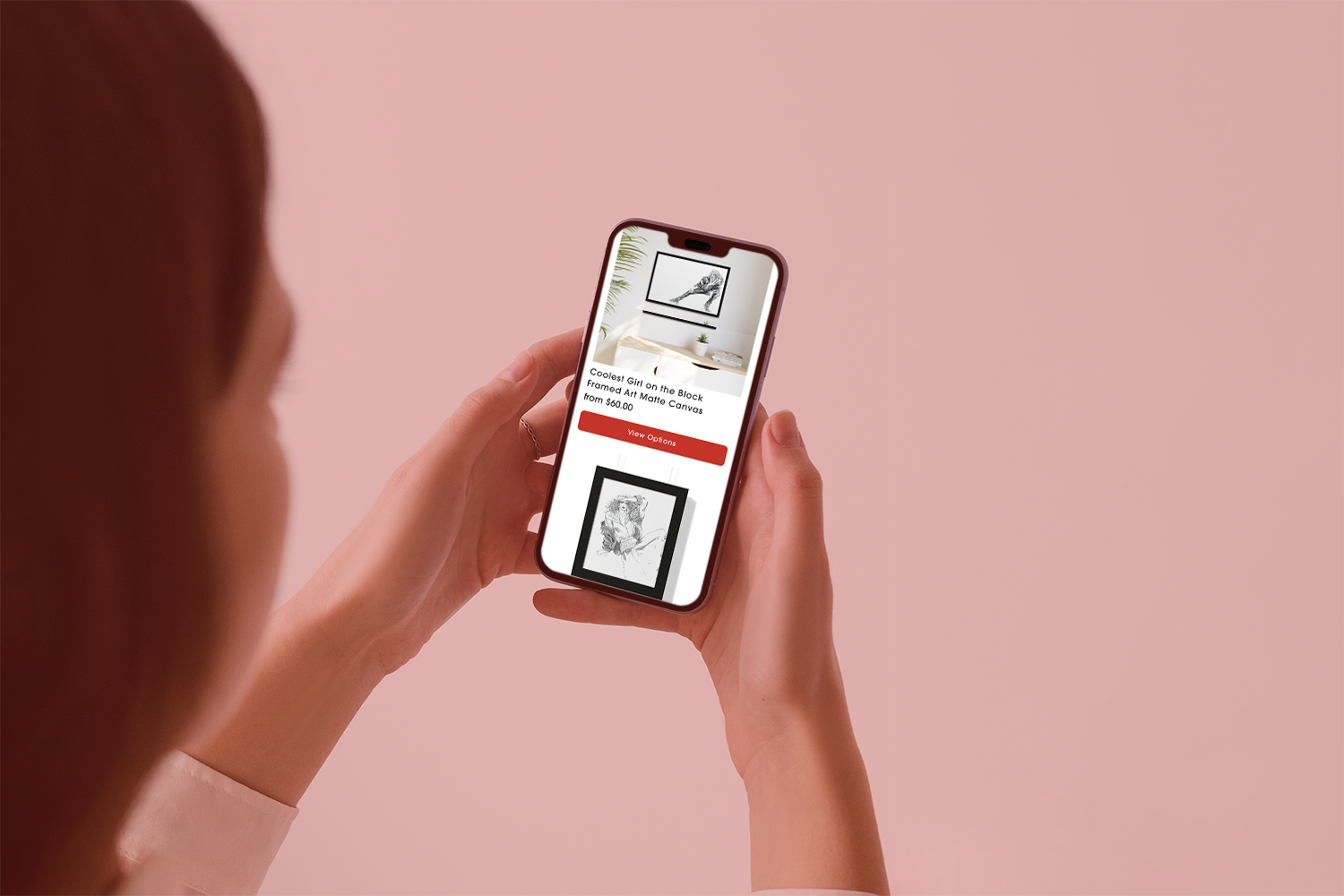 Person holding a smartphone with an online art shopping website open, displaying a framed artwork of a girl on a block.