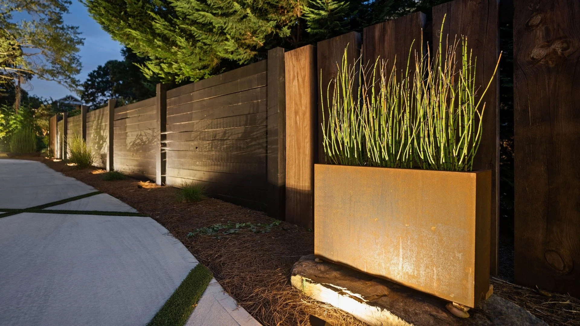   Modern Fence & Pathway Lighting  
Contemporary fence lighting with pathway LED lights, creating a warm, inviting ambiance along a landscaped walkway. Thoughtfully placed fixtures highlight architectural and natural elements.