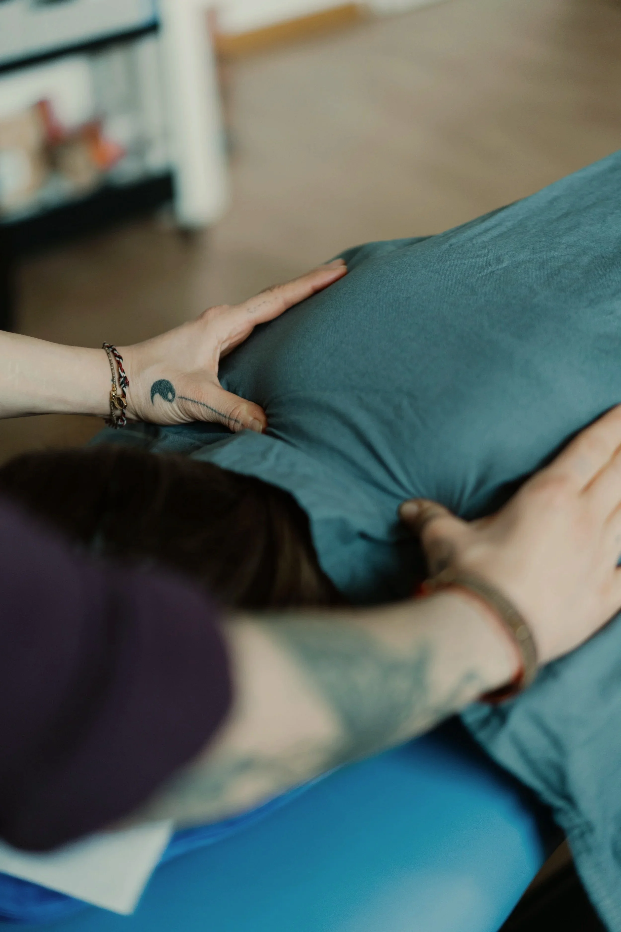 Nahaufnahme einer Person, die auf einer Liege liegt, mit einer Hand, die auf dem Bauch ruht.