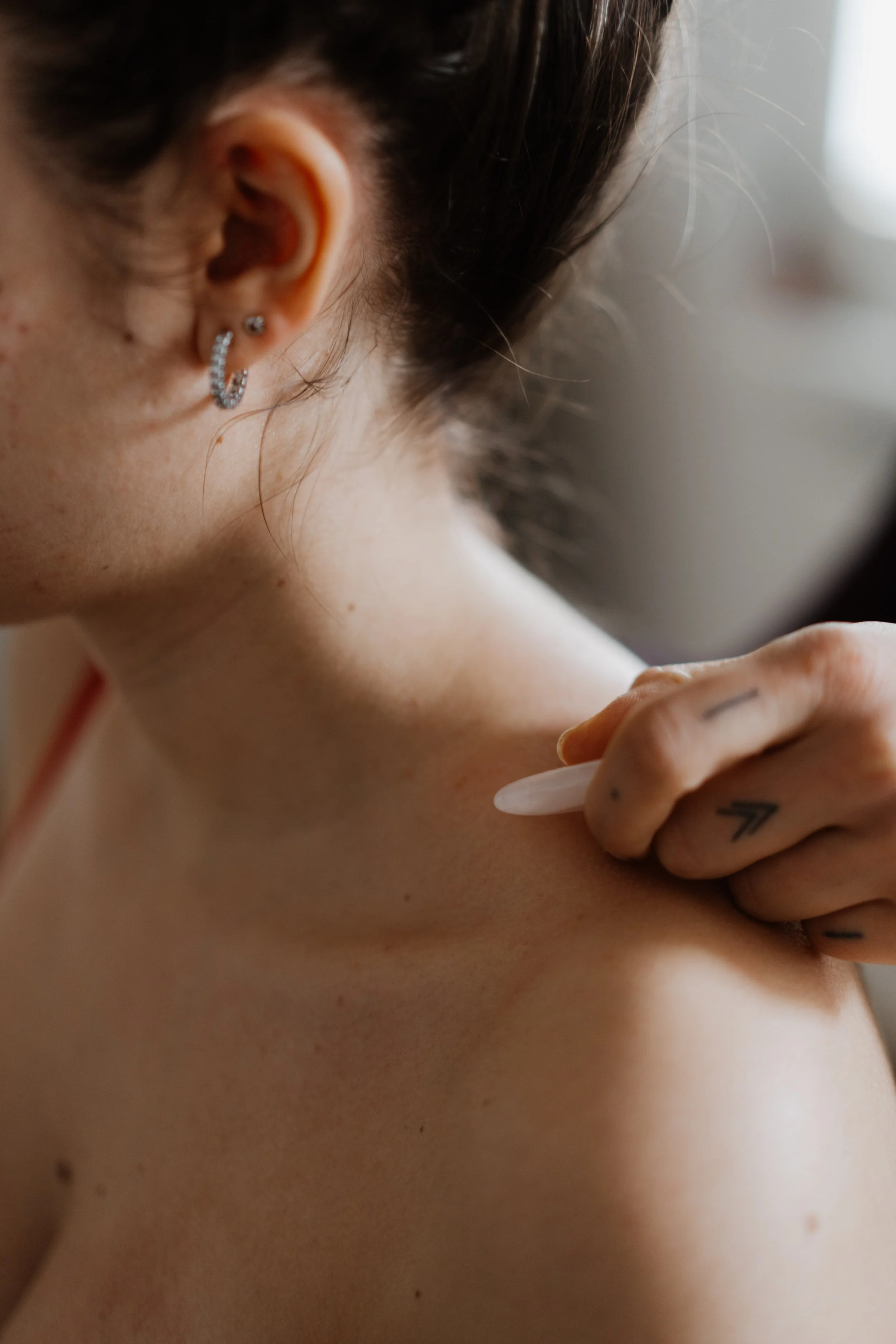 Nahaufnahme eines Frauenhalses, an dem ein Gua Sha Stein eingesetzt wird