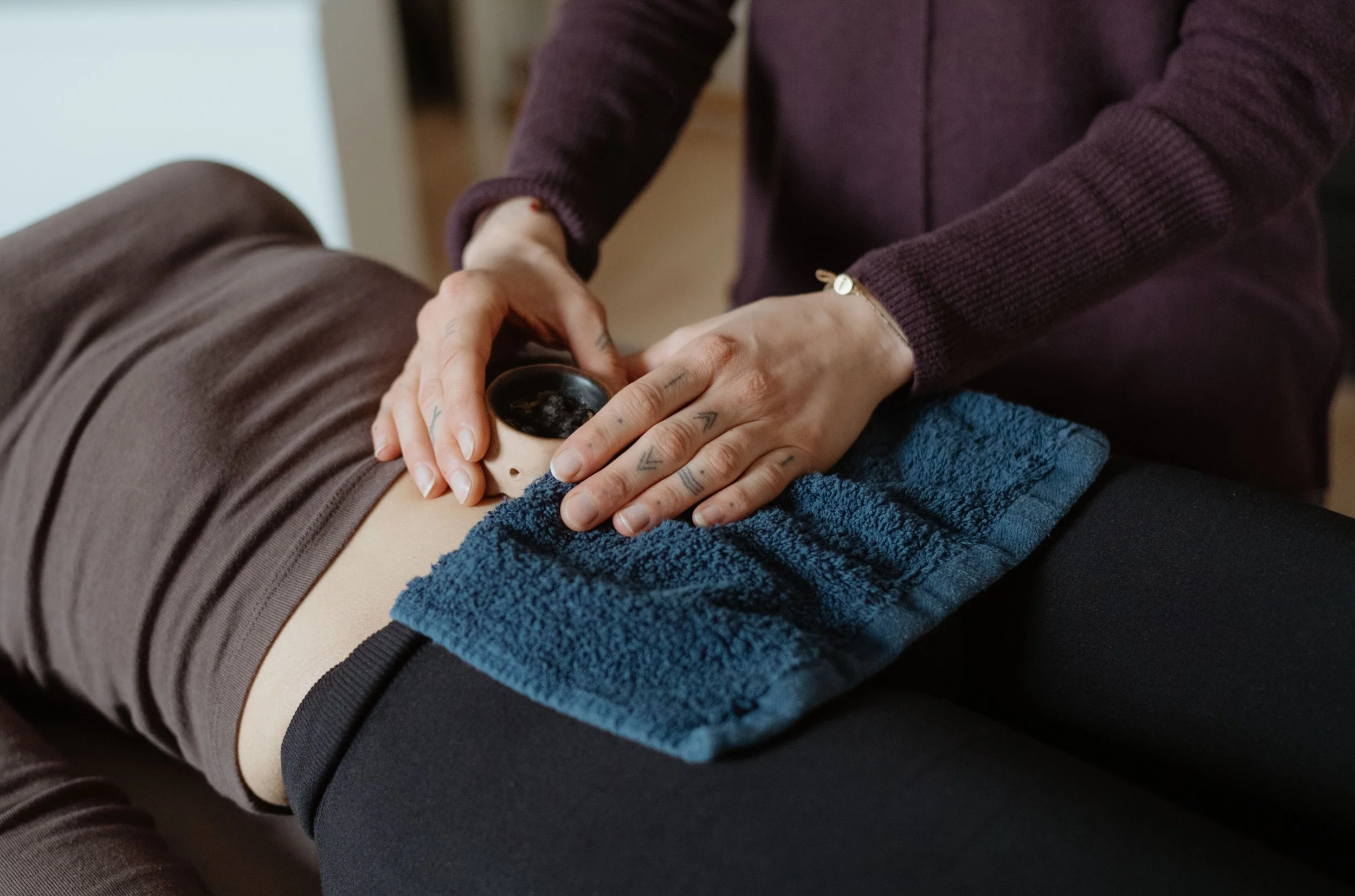 Eine Person führt eine therapeutische Behandlung bei einer Frau auf einer Liege durch.
