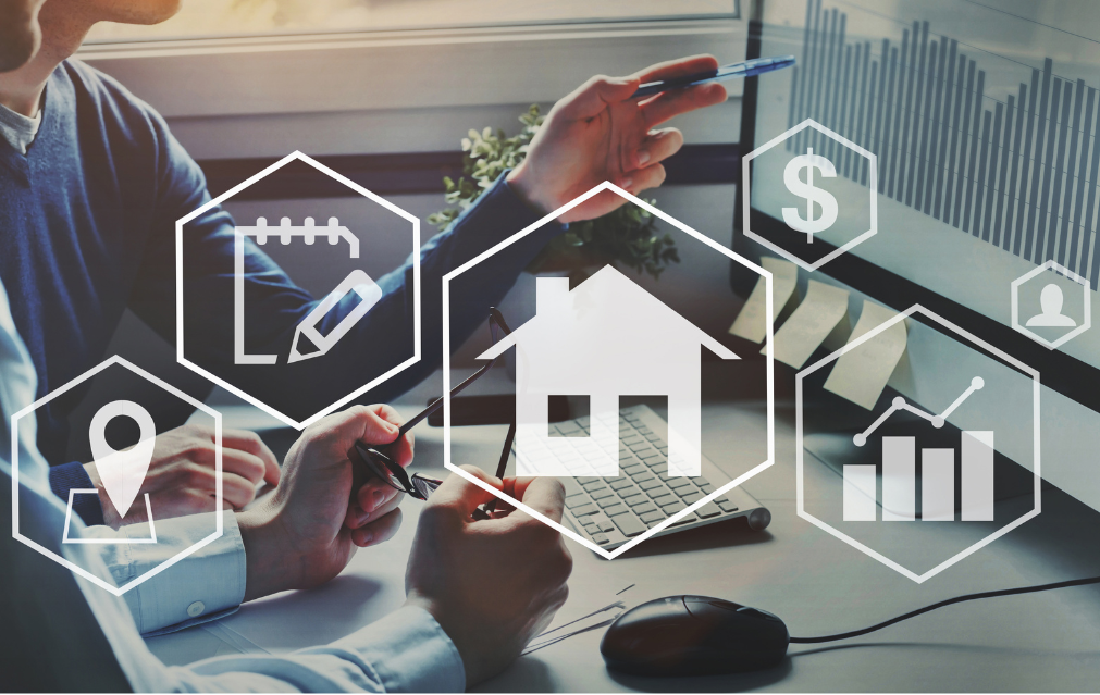 Two people discussing real estate investment or property market data on a computer screen, with overlay icons representing house, money, chart, location, and writing.