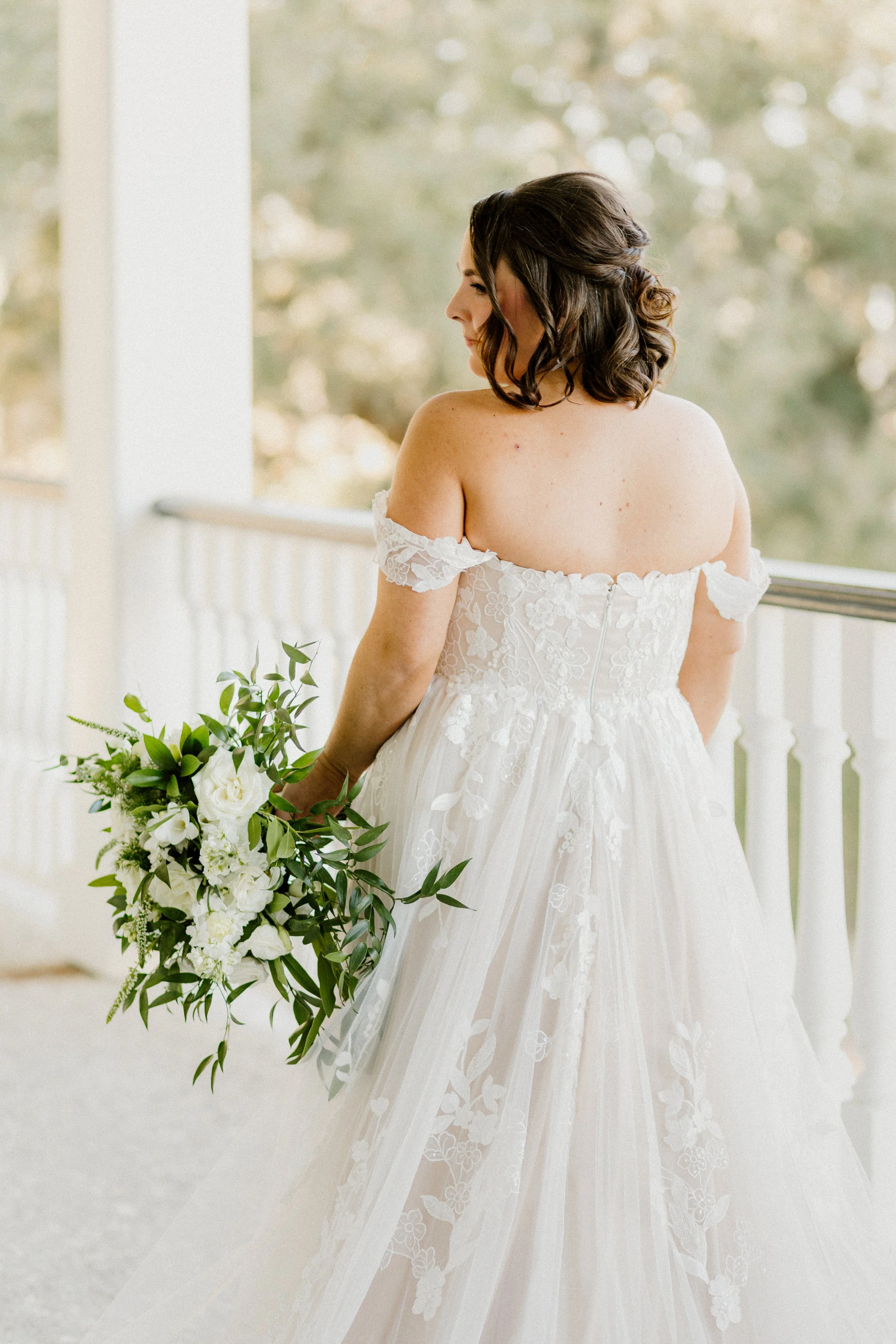Bride photographed from behind highlighting wedding dress details and bouquet