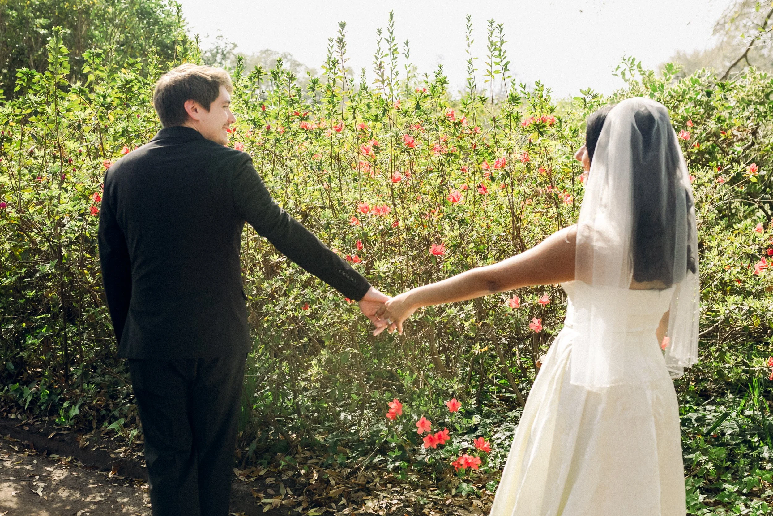 Bride and groom holding hands in colorful garden during Lowcountry wedding