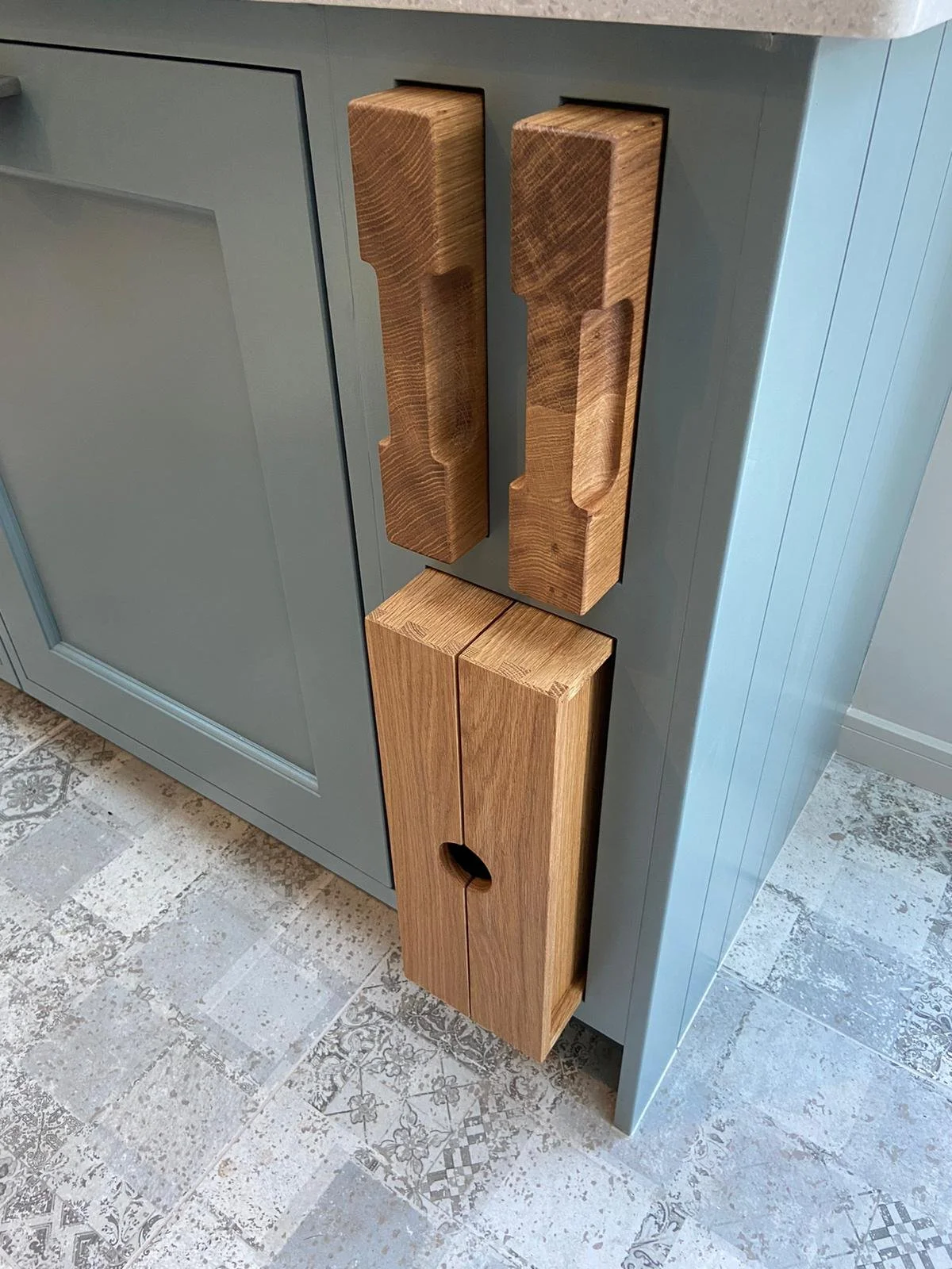 One side of a kitchen island unit showing bespoke storage for chopping boards and trays.