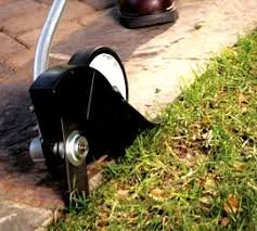 Lawn edger cutting grass near a sidewalk