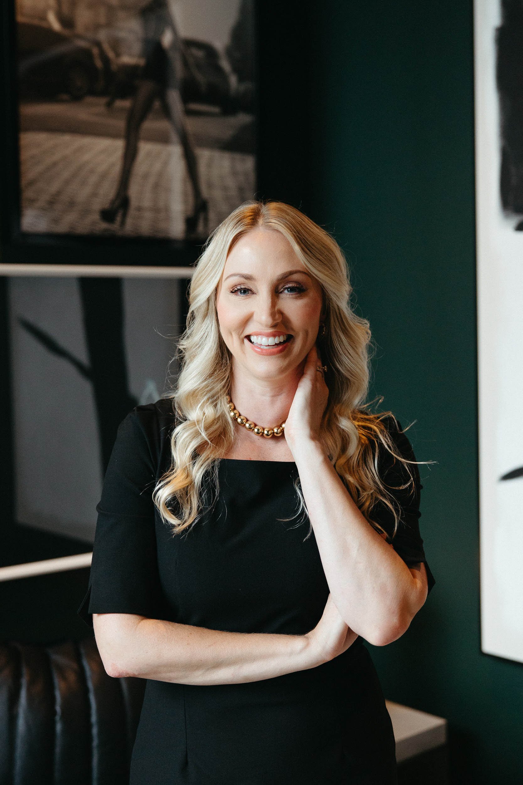 Confident personal injury lawyer Whitney in black dress with blonde hair and a smile.