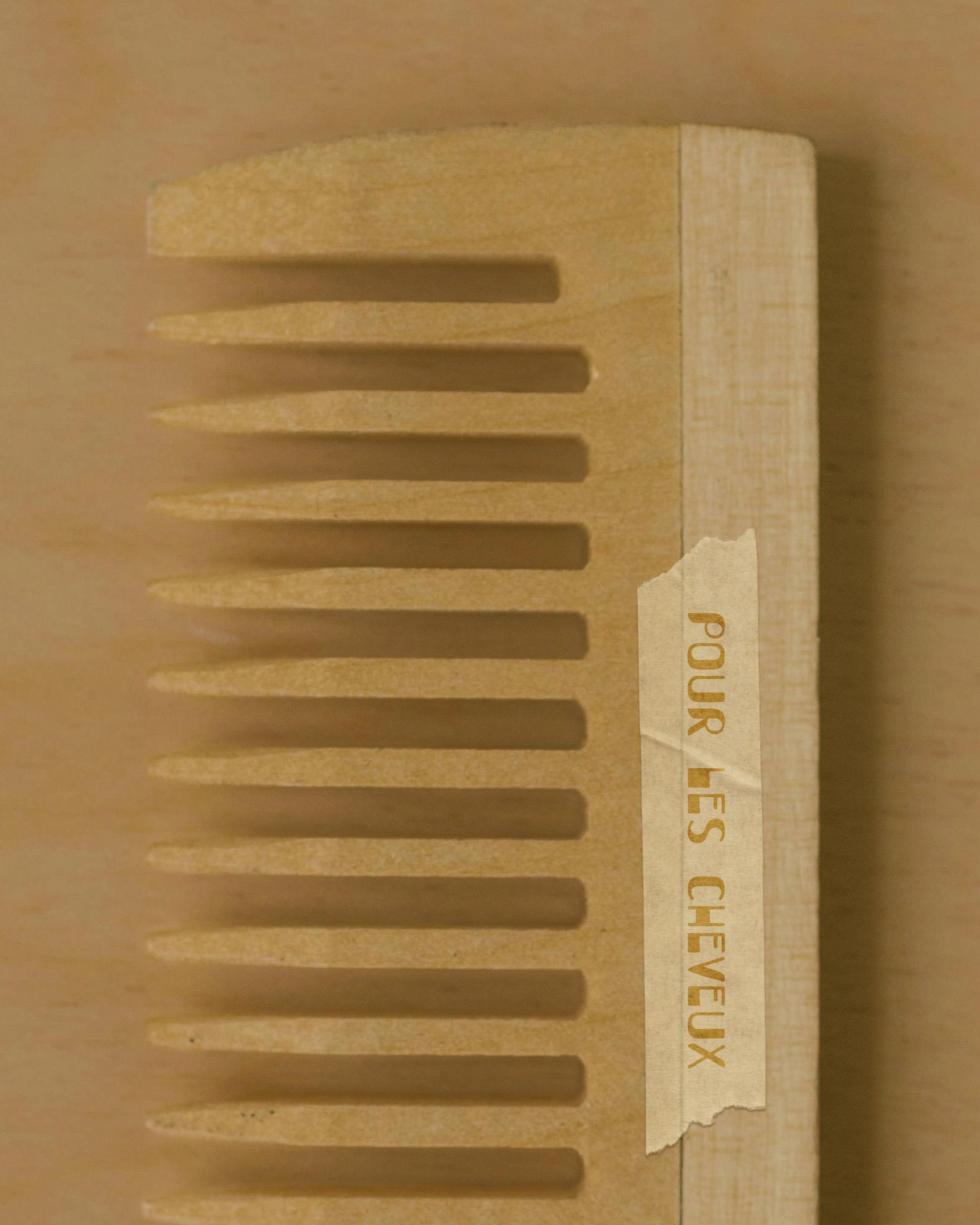 Wooden comb editorial lifestyle product featuring hand drawn lettering from By Hand Design's Tre Palme font on a natural product label, illustrating how handcrafted typography enhances artisanal branding and premium packaging design.