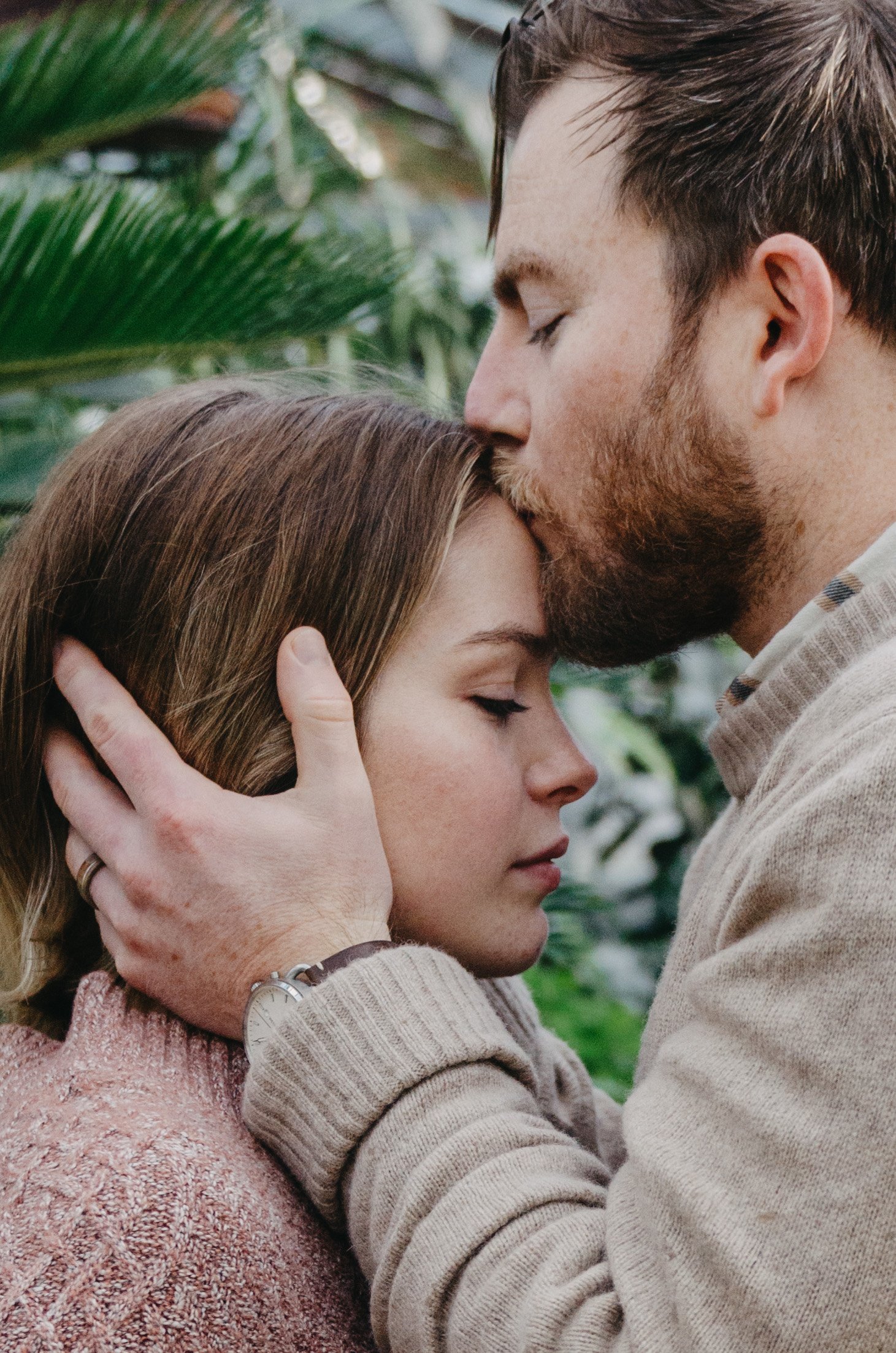 Couple sharing a warm embrace in a greenhouse on a cold winter day