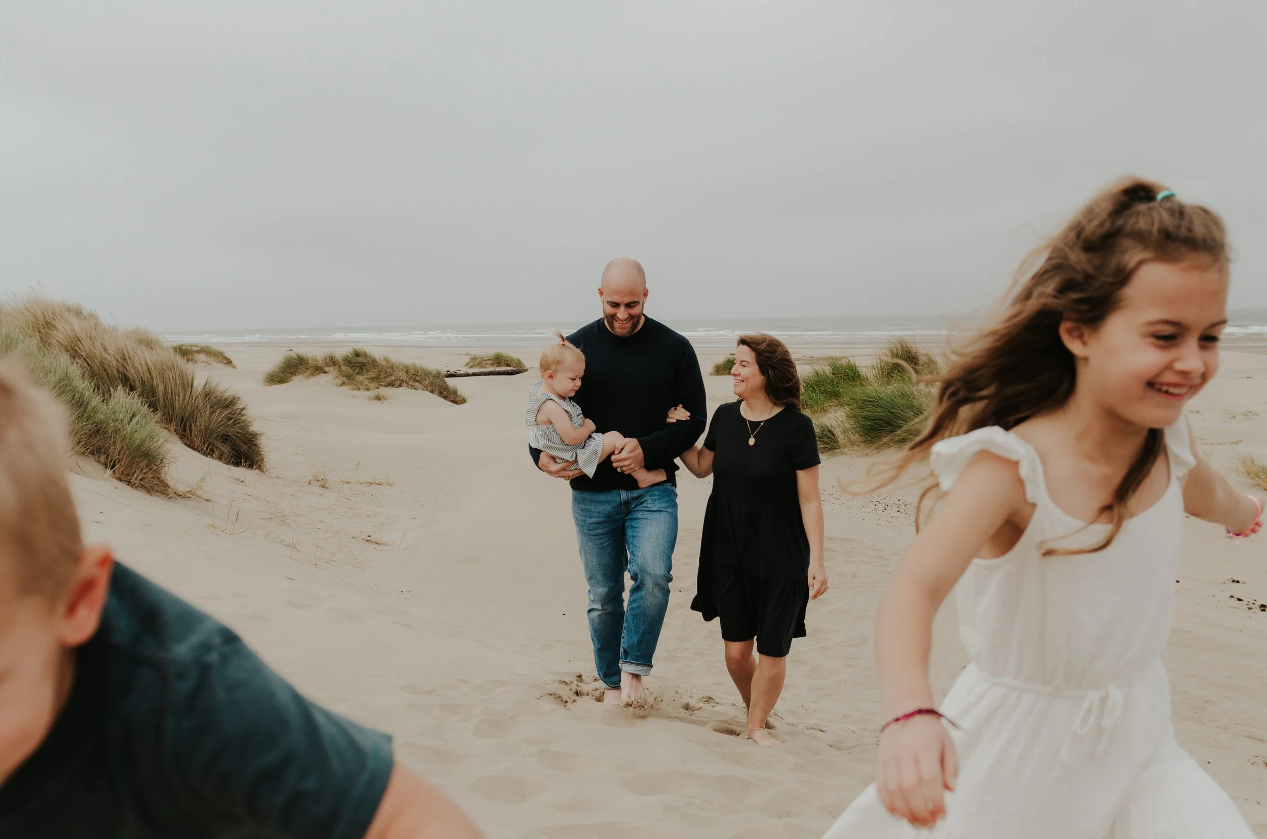 Oregon coast family photography session of parents and kids running at the beach