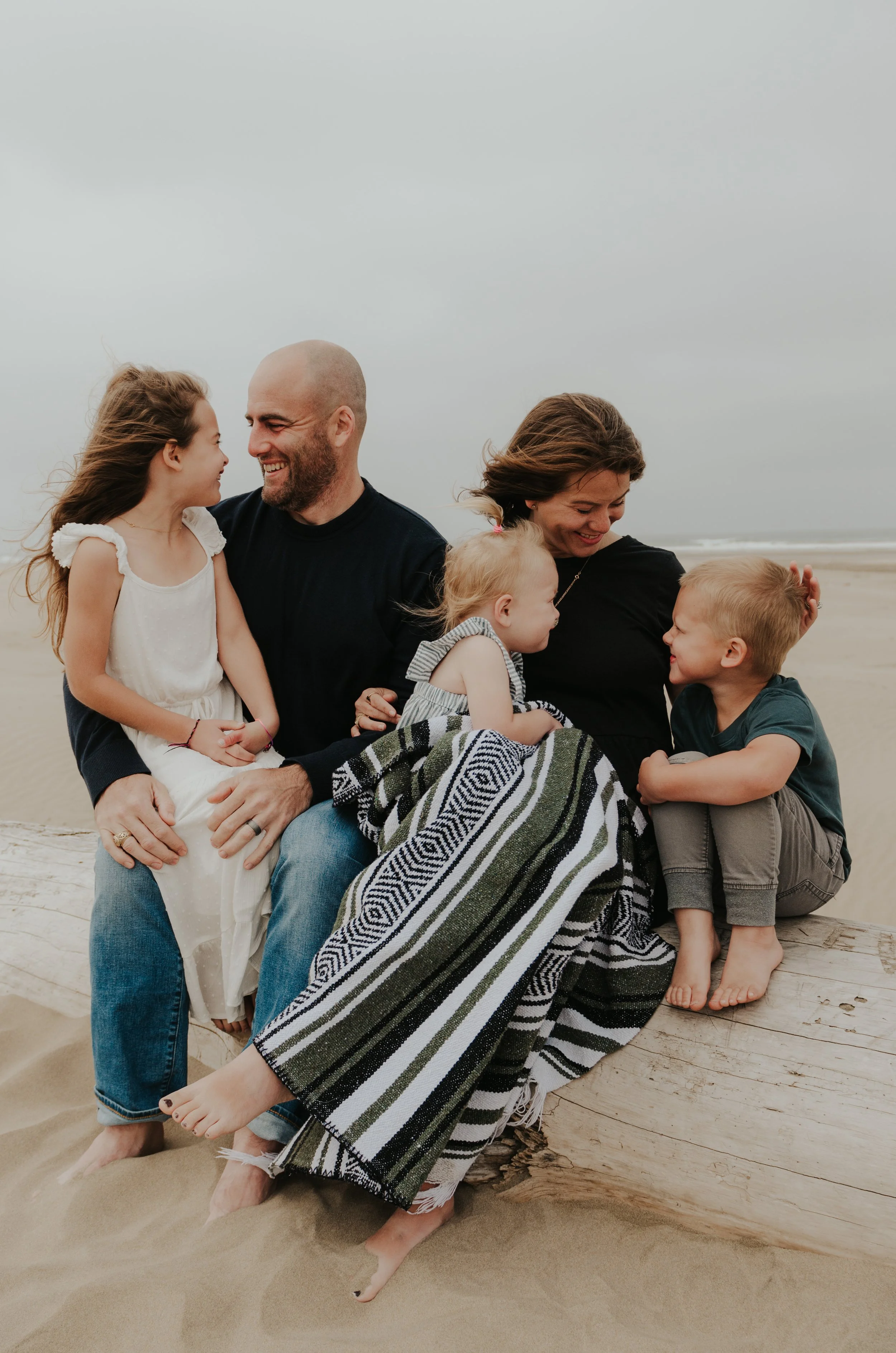 Oregon coast family photography session of parents and kids cuddling on a log
