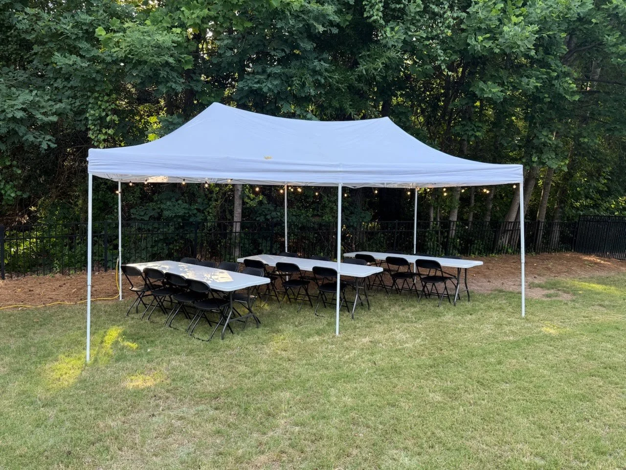 10x20' tent with 8-ft tables and string lights underneath