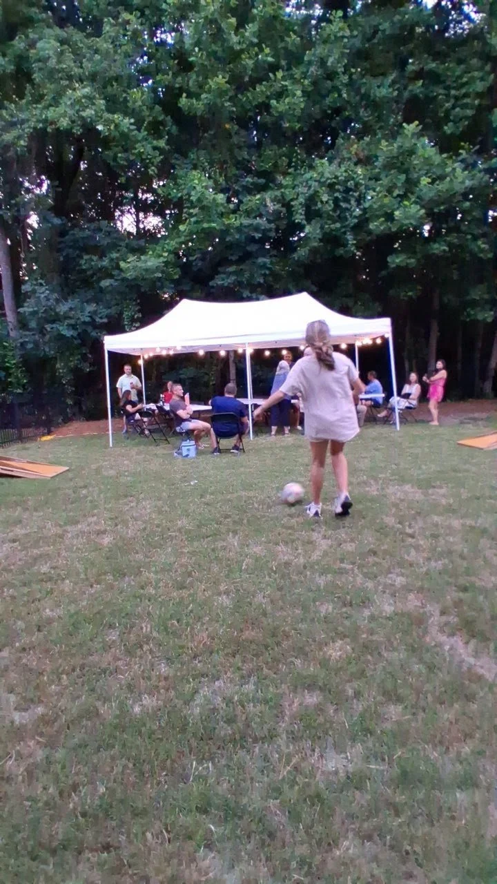 kids playing soccer in front of party tent