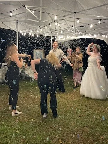 People celebrating under a wedding tent with string lights