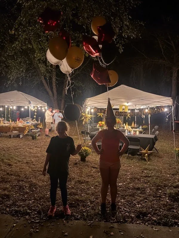 kids holding balloons in front of tent at night with string lights