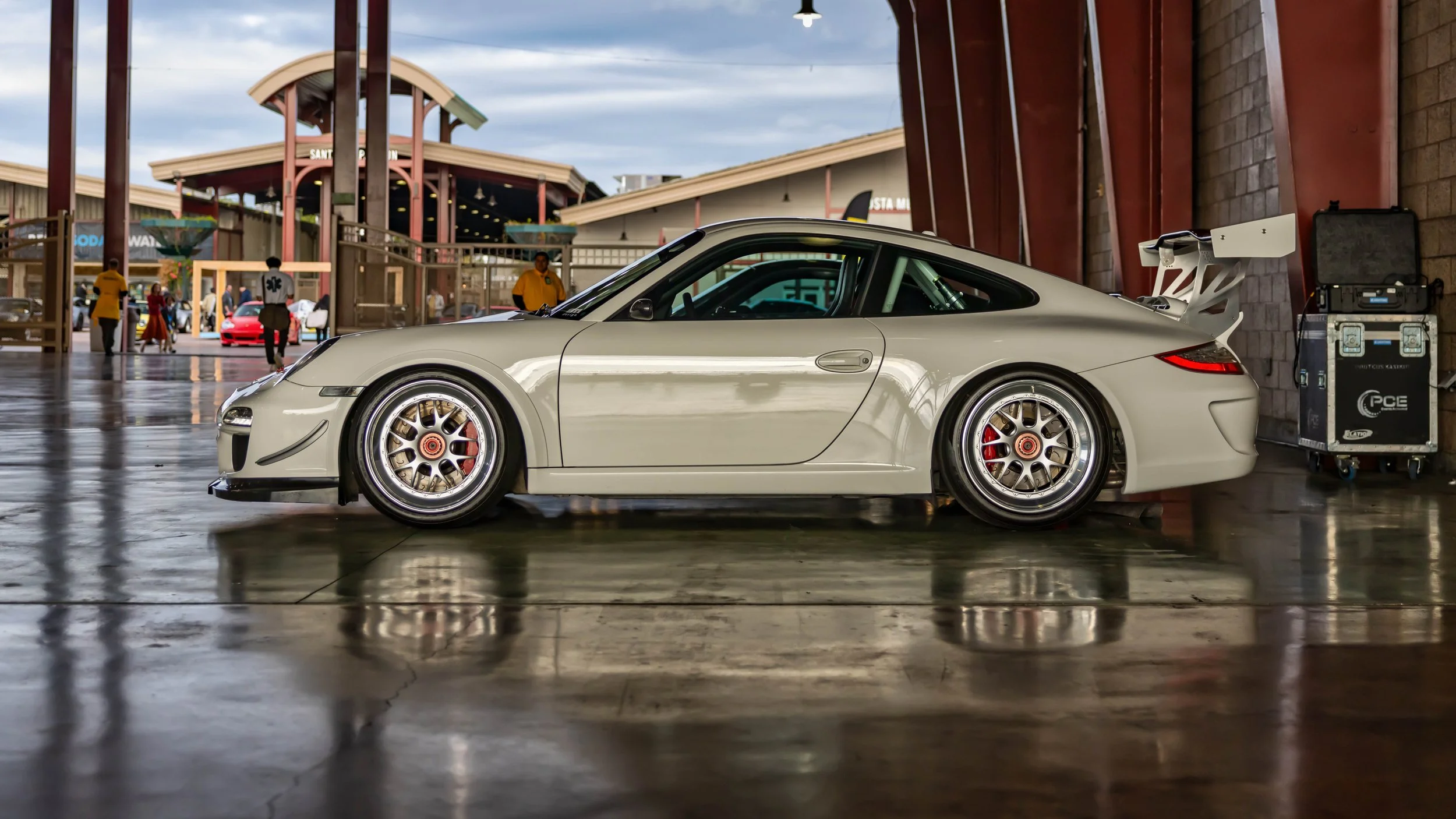 Air | Water 2025 — Orange County Fairgrounds — A side profile view of a light gray, track-prepared Porsche 997.1 911 GT3 parked indoors on a highly reflective, polished concrete floor. The car is heavily modified with multi-piece mesh-style wheels wi