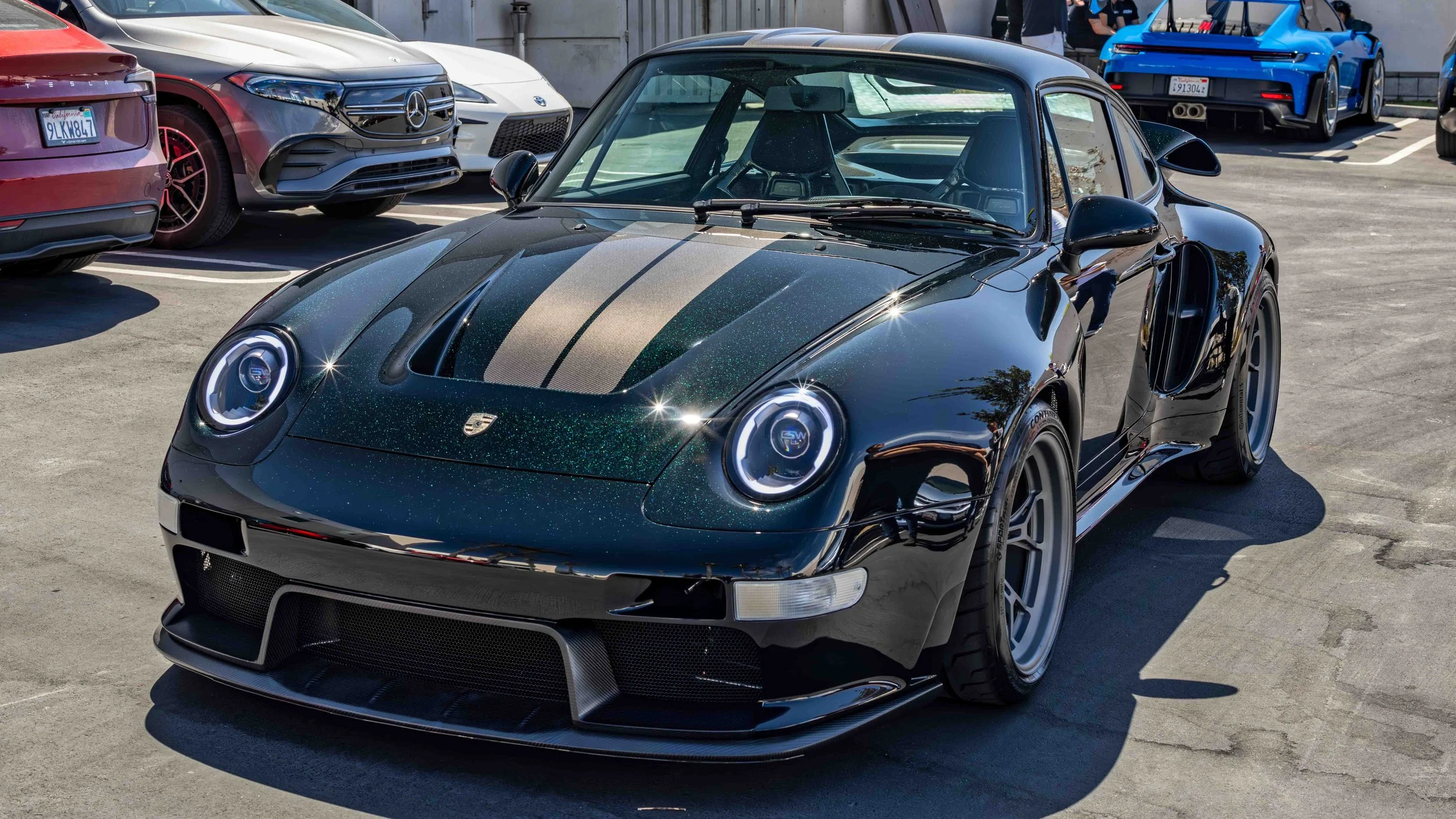 Turbo Florio 5 — NVIDIA Black Metallic 1996 Gunther Werks remastered Porsche 911 Turbo (993) parked in the sun outside  Gunther Werks headquarters, left front‑three‑quarter view with exposed carbon-fiber stripe and with green metallic flake. — #Turbo