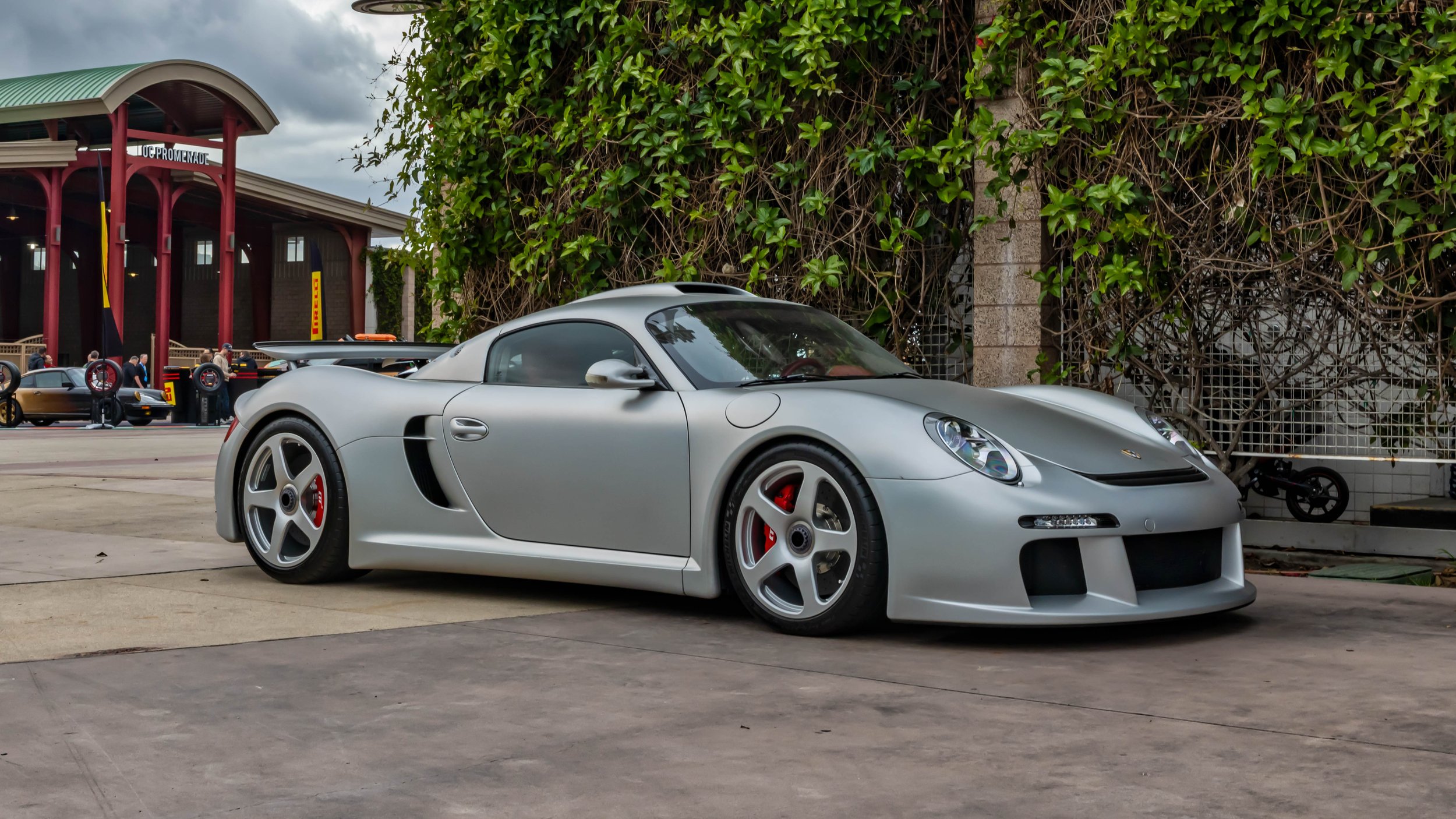 Air | Water 2025 — Orange County Fairgrounds — A silver RUF CTR3 is parked on a paved surface, captured from a low front three-quarter angle. This mid-engine supercar features distinctive center-lock, six-spoke wheels with red RUF-branded brake calip