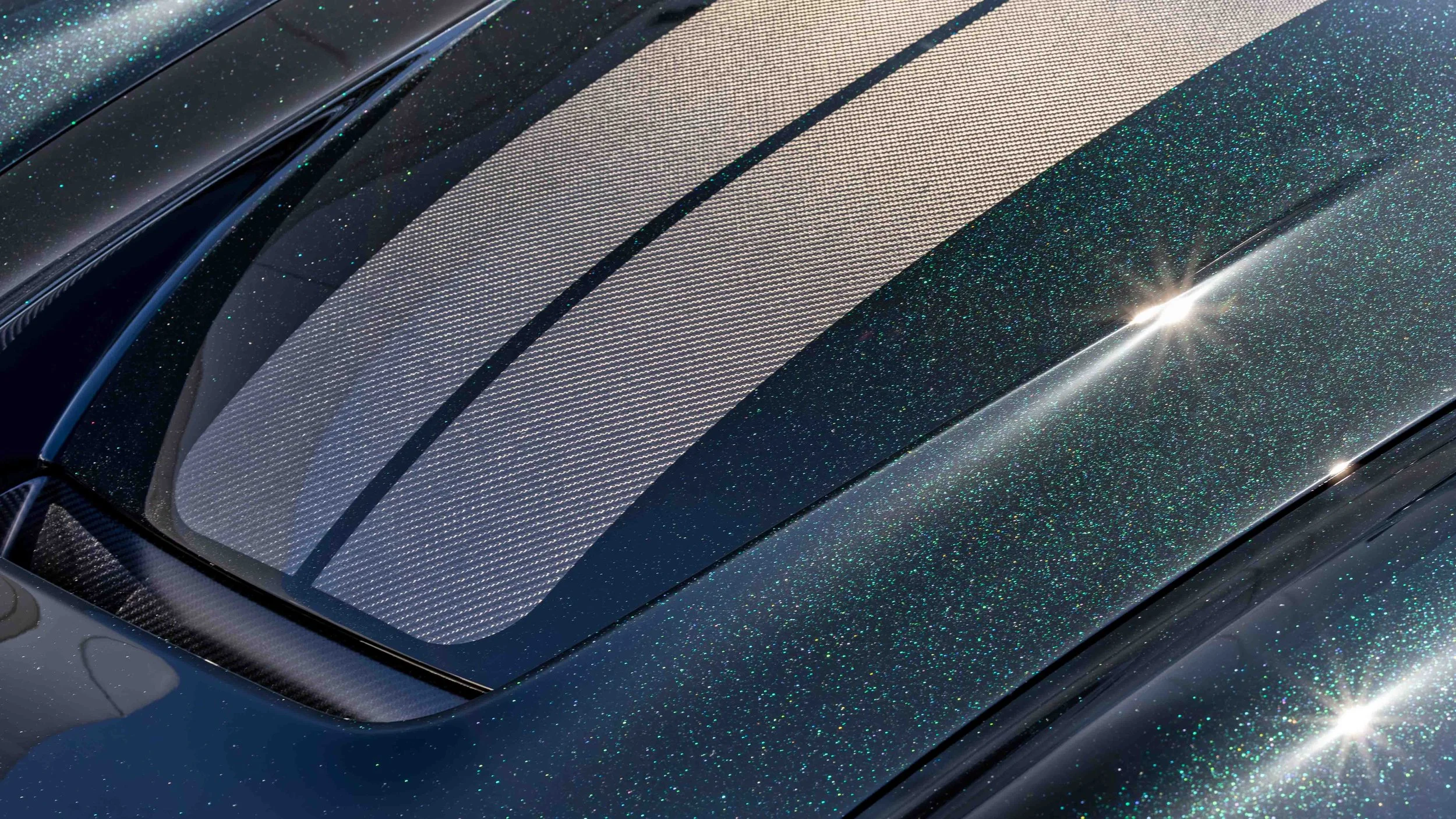 Turbo Florio 5 — Close up of hood of NVIDIA Black Metallic 1996 Gunther Werks remastered Porsche 911 Turbo (993) parked in the sun outside  Gunther Werks headquarters, with exposed carbon-fiber stripe and with green metallic flake. — #TurboFlorio5
