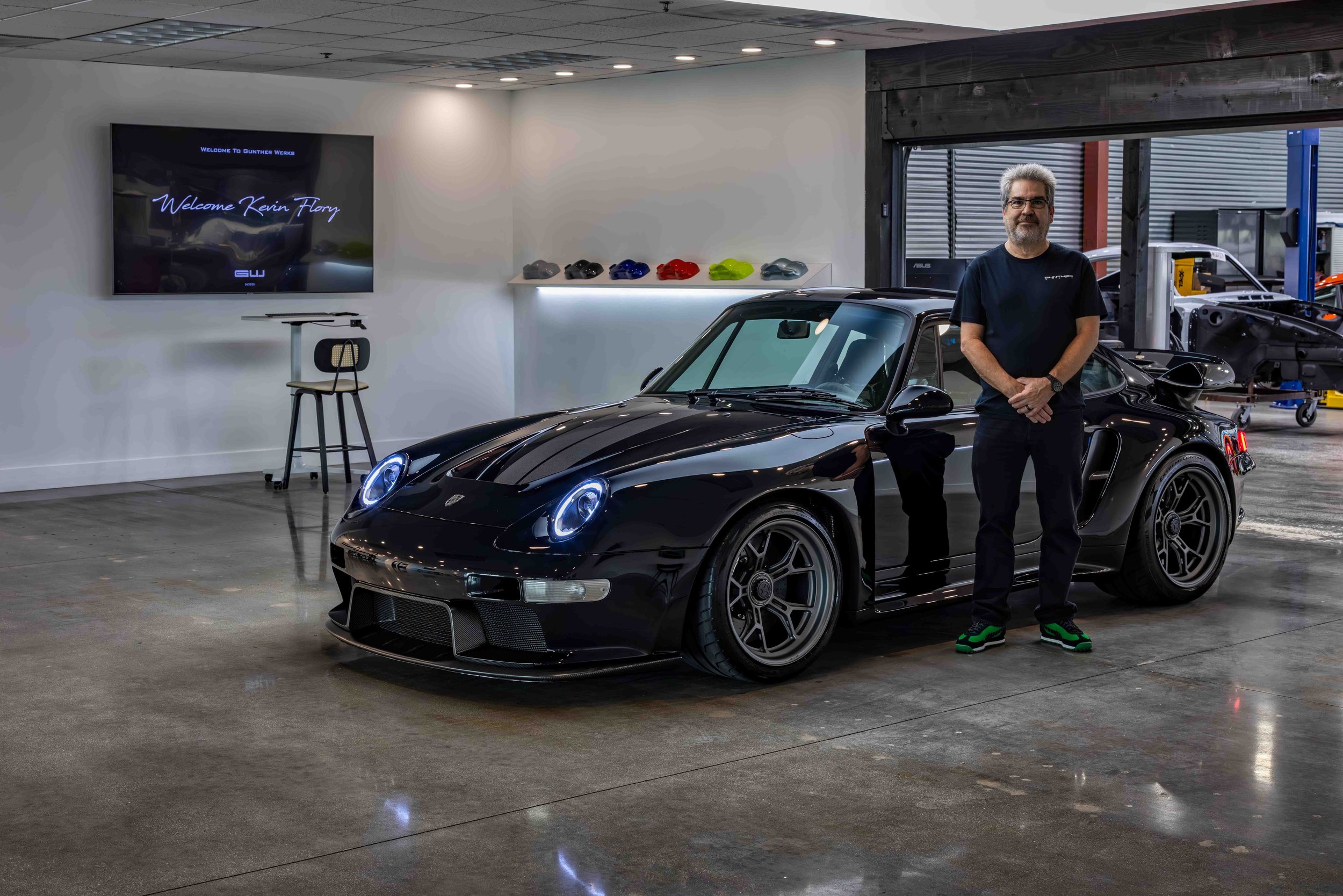 Turbo Florio 5 — NVIDIA Black Metallic 1996 Gunther Werks remastered Porsche 911 Turbo (993) parked in the Gunther Werks showroom, left front‑three‑quarter view with proud owner after taking delivery. — #TurboFlorio5
