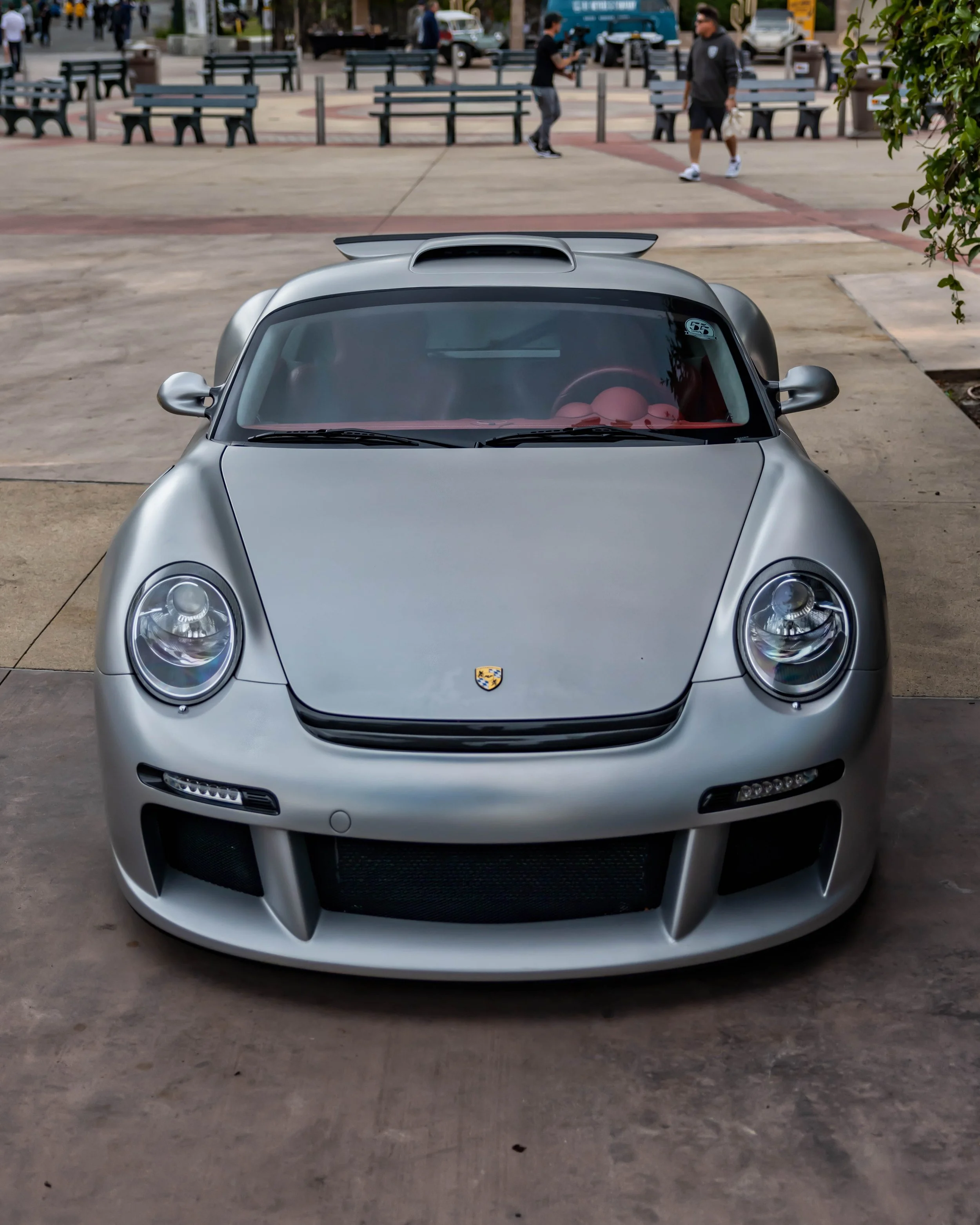 Air | Water 2025 — Orange County Fairgrounds — A head-on, slightly elevated view of a matte silver Ruf CTR3 parked in a public plaza. The car features a custom front bumper with LED daytime running lights, a roof-mounted air scoop, and a vibrant red 