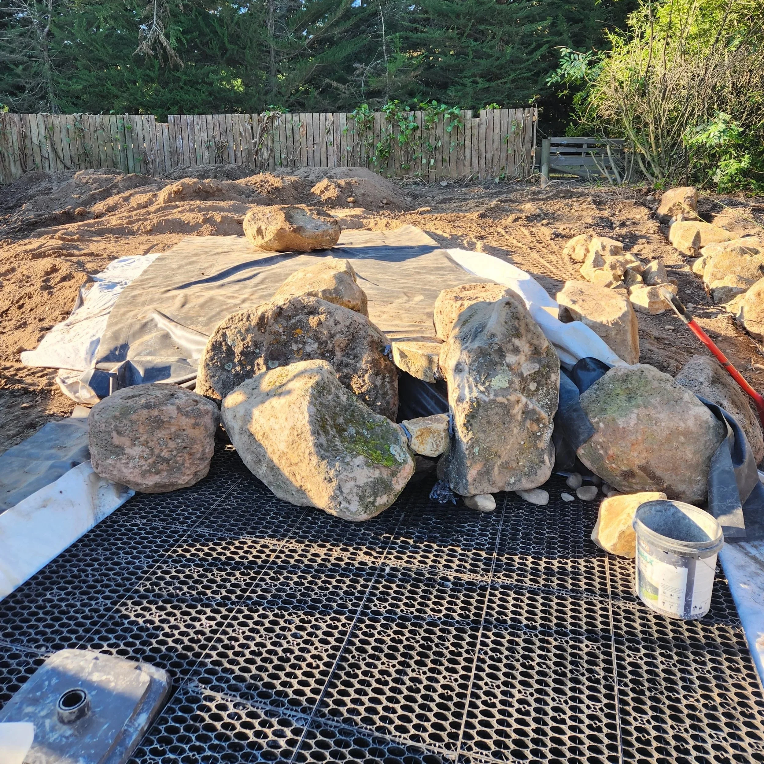 Natural boulder placement over Aquascape reservoir and liner — pondless waterfall build, Aylesbury Selwyn