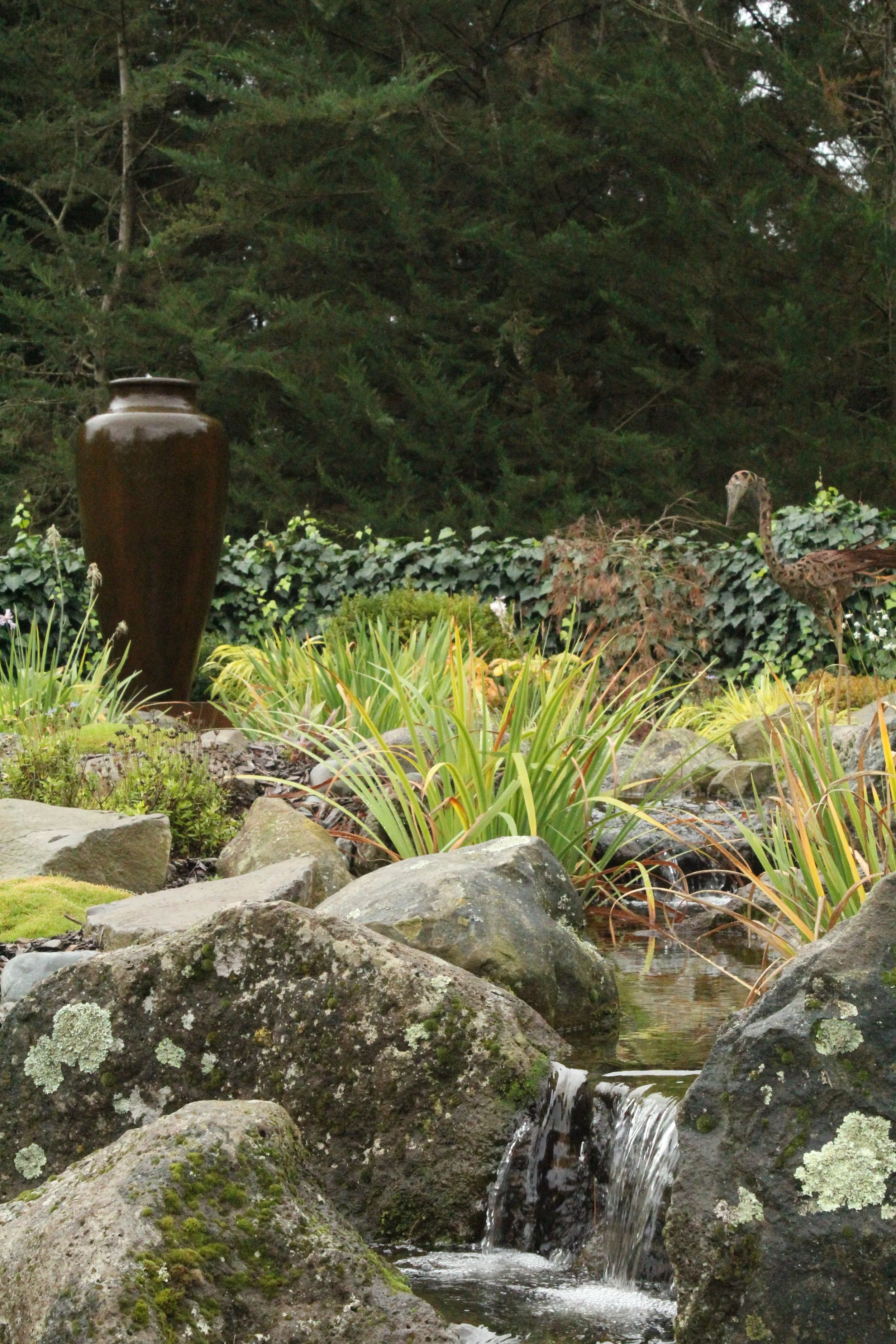 Ecosystem pond with ornamental urn, metal heron sculpture and flax planting in Selwyn Canterbury by Southern Waterscapes