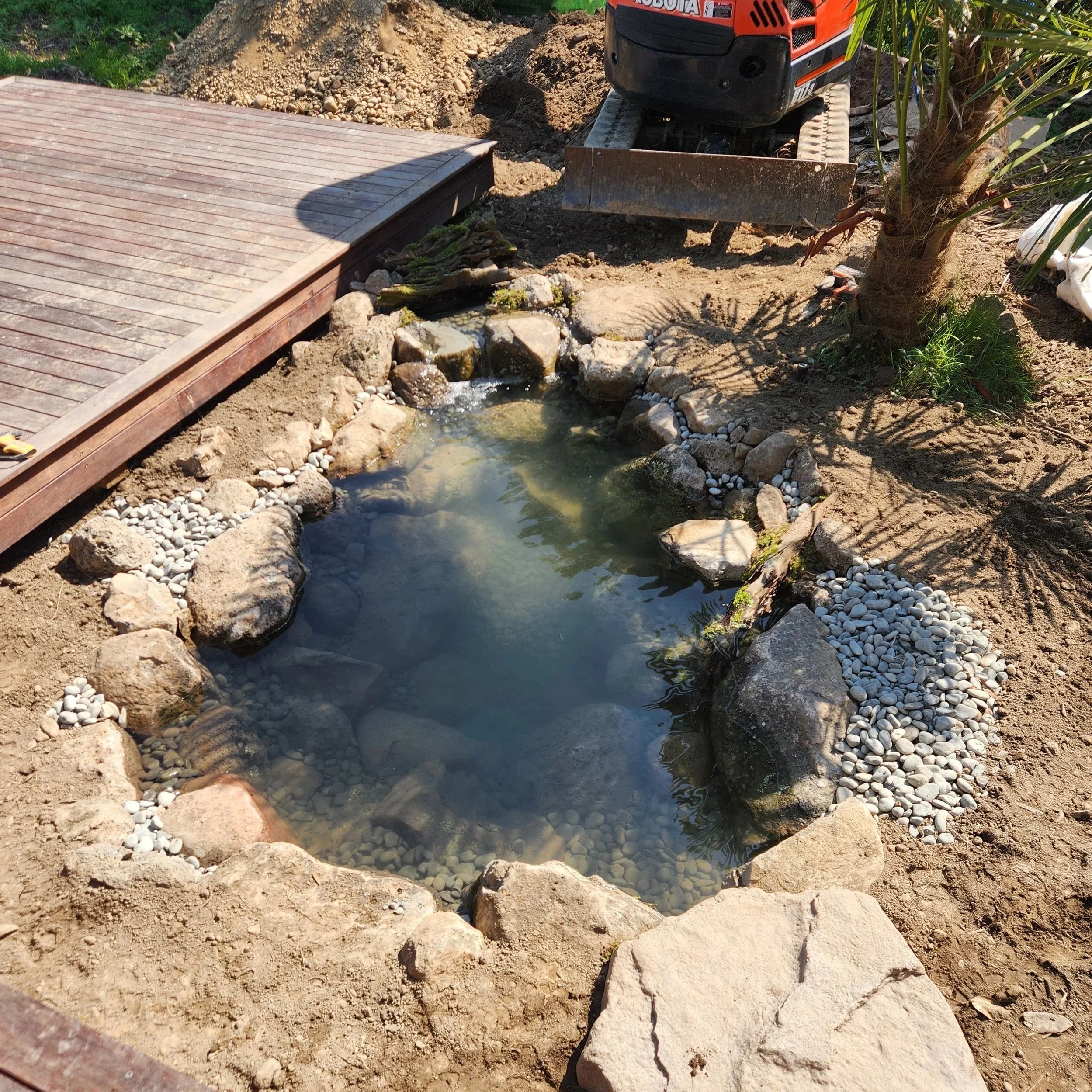 Eco-system pond near completion with timber deck integration and pebble edging — Southern Waterscapes Ltd, Selwyn Canterbury