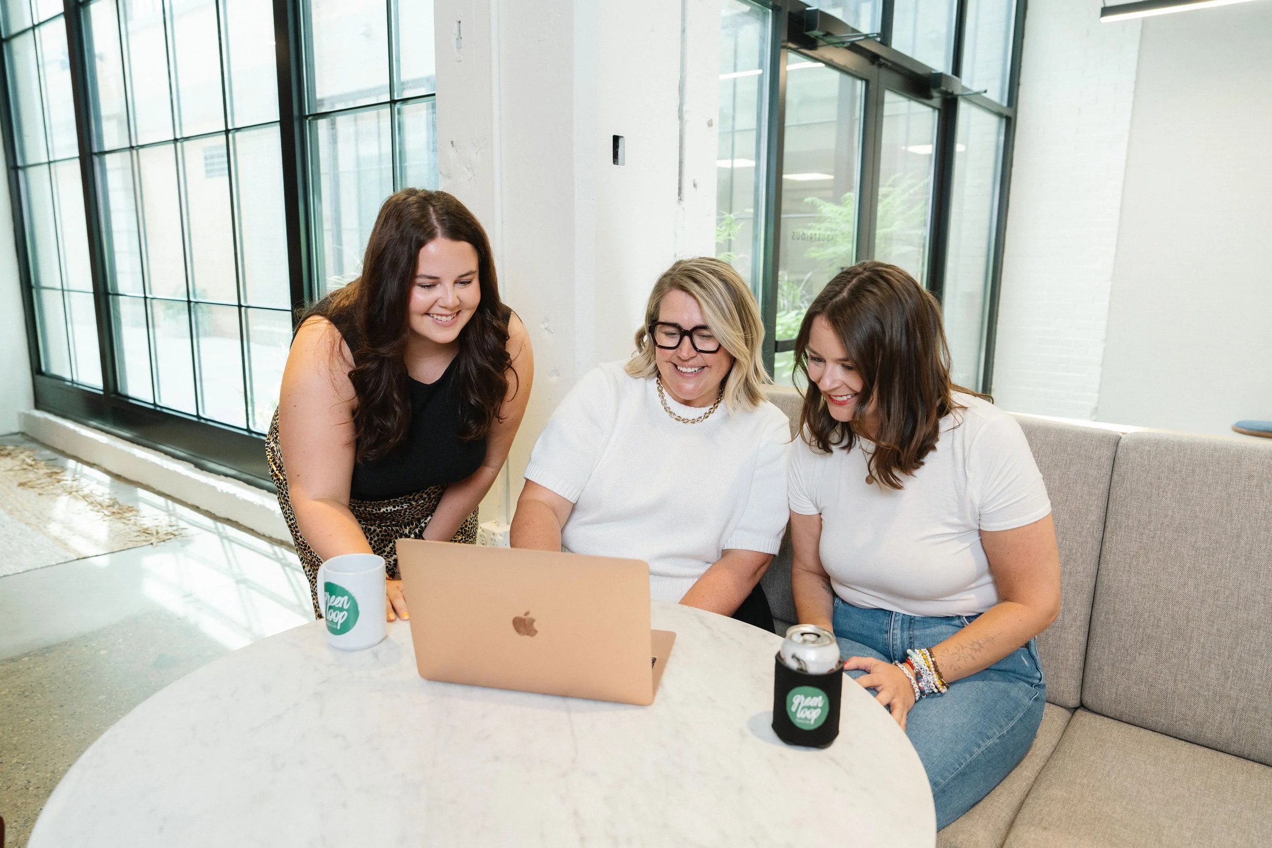 Three Green Loop team members looking at a laptop together.