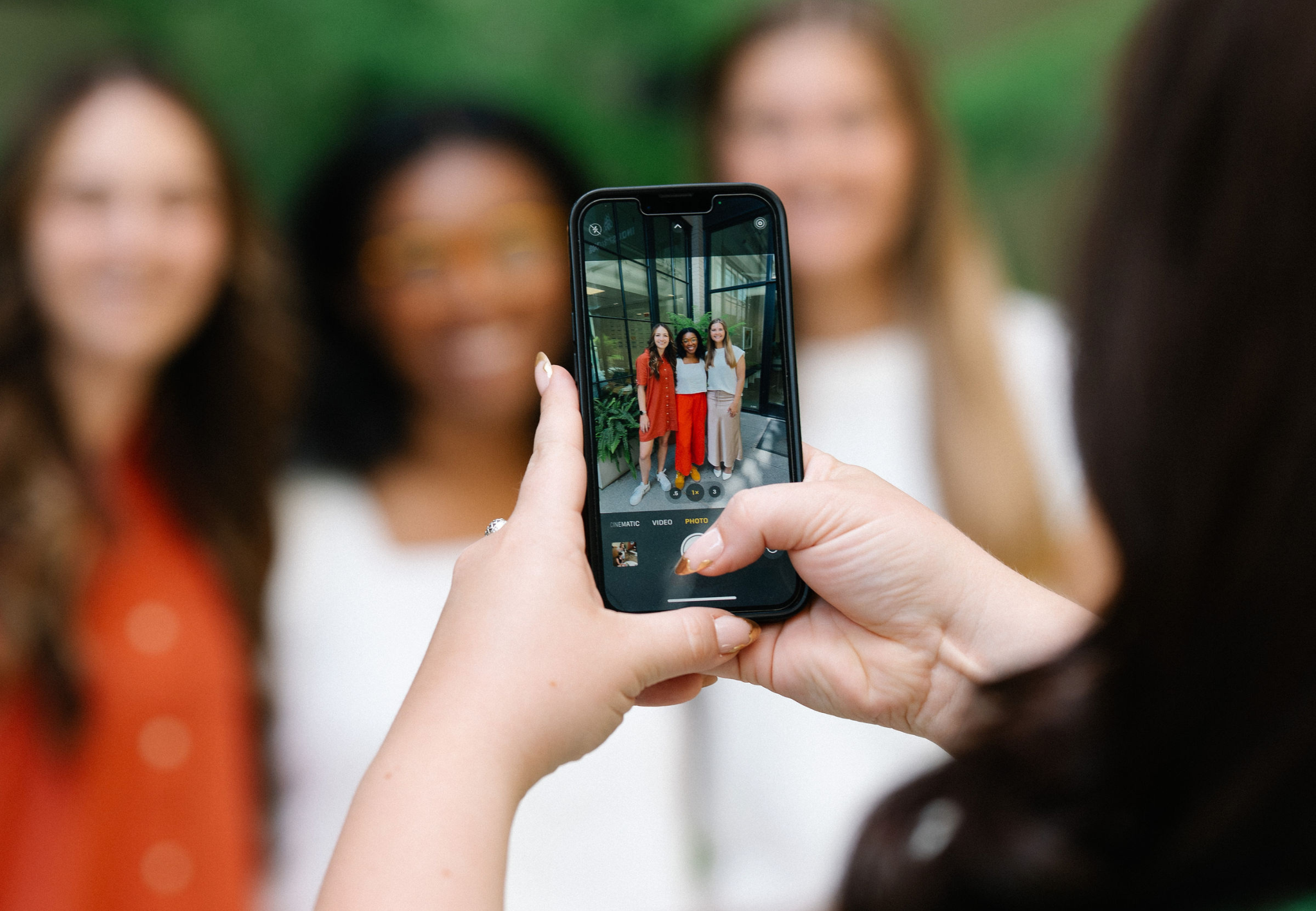 A cellphone being used to capture a photo of three women