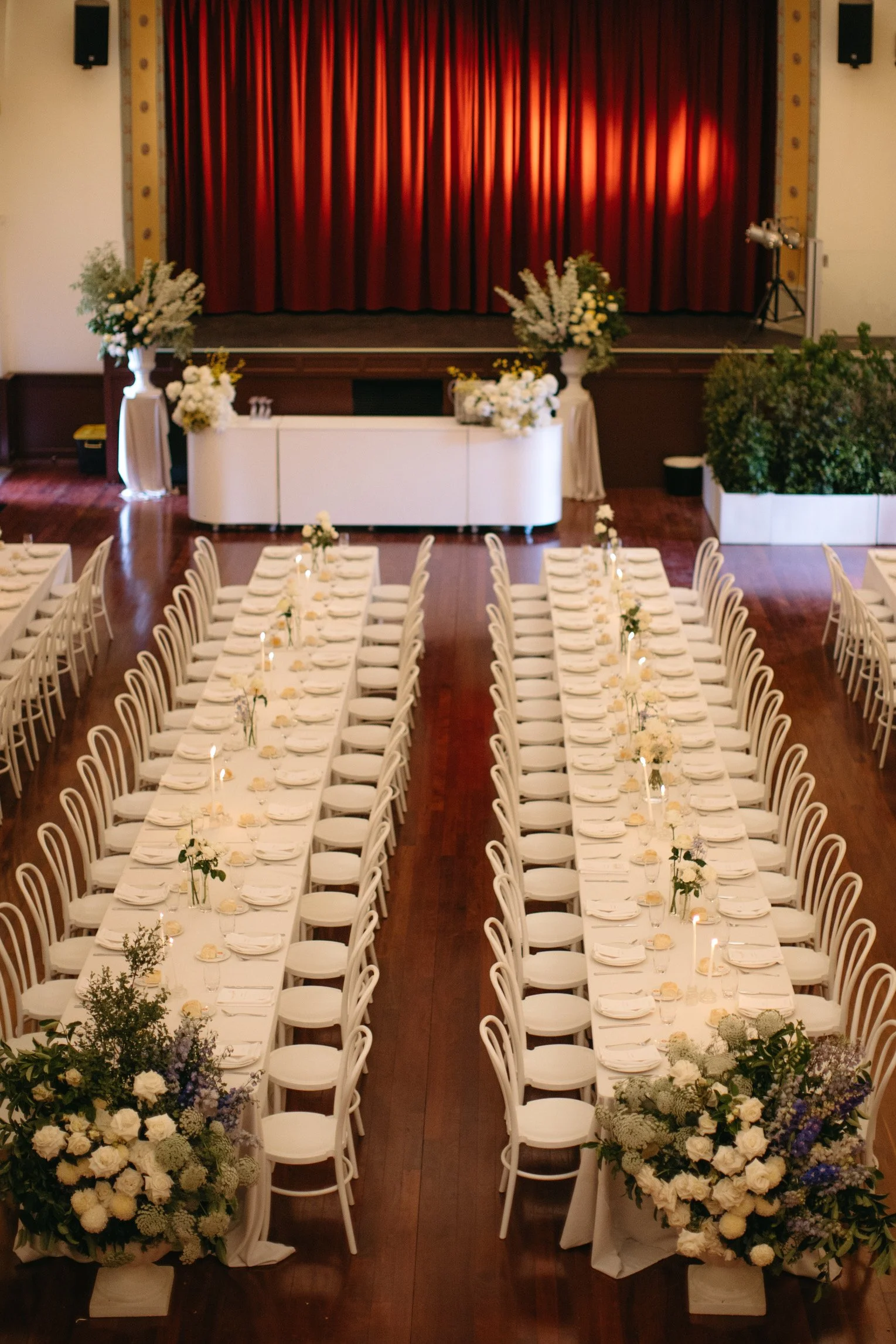 Long wedding tables lined with white bentwood chairs inside Deniliquin Town Hall.