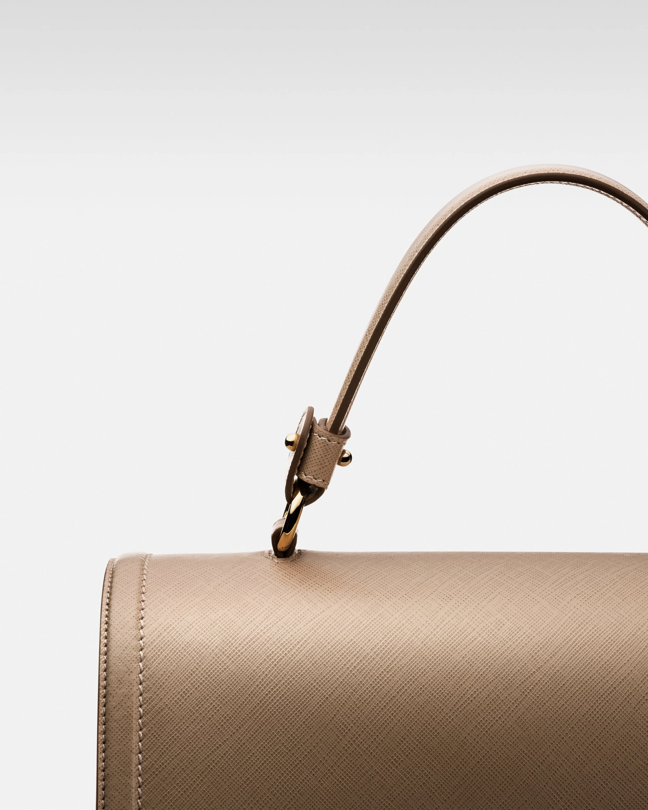Close-up of a beige textured handbag with a curved strap and gold hardware, against a plain white background.