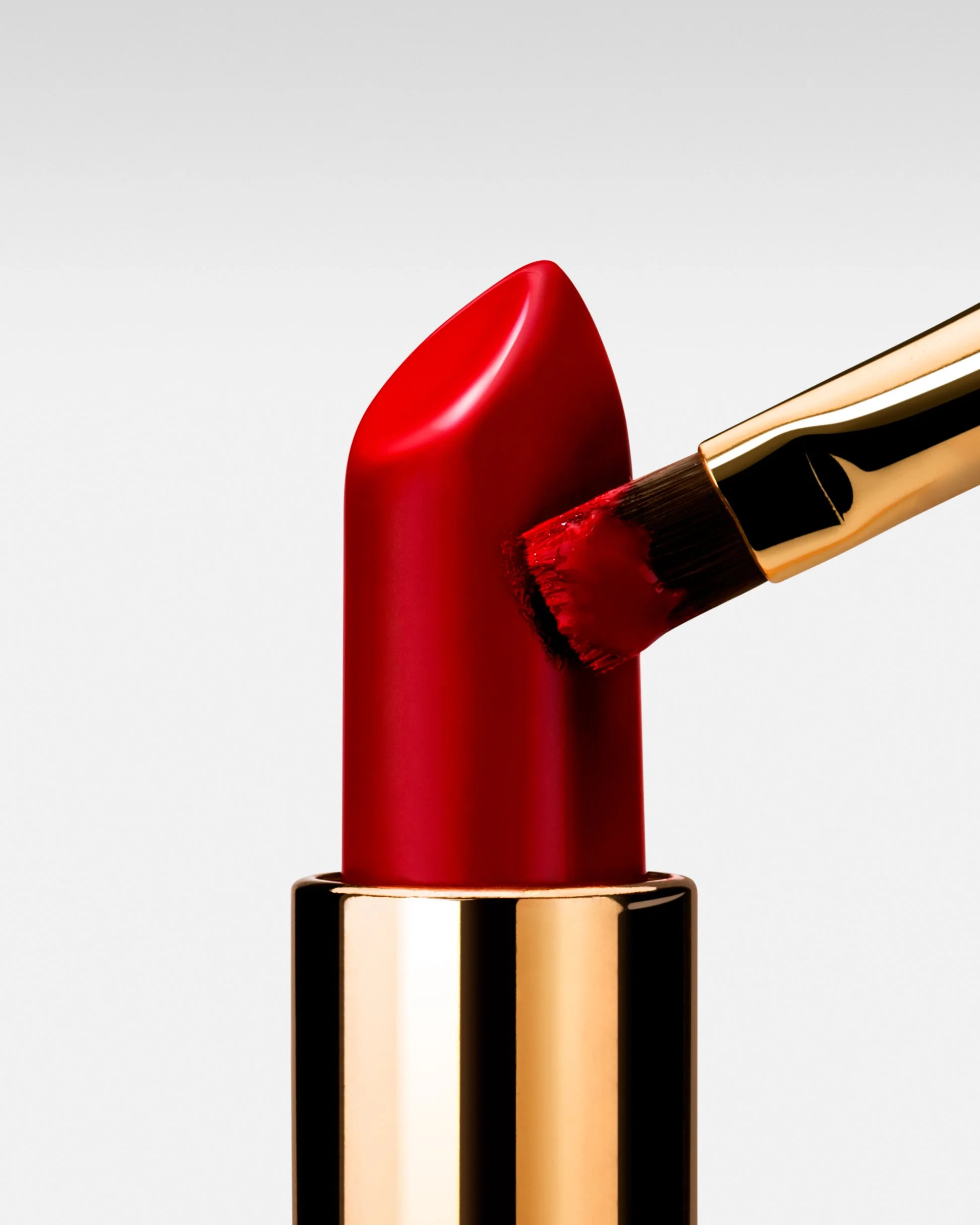 Close-up of a red lipstick tube with the cap removed, revealing the lipstick, against a white background.