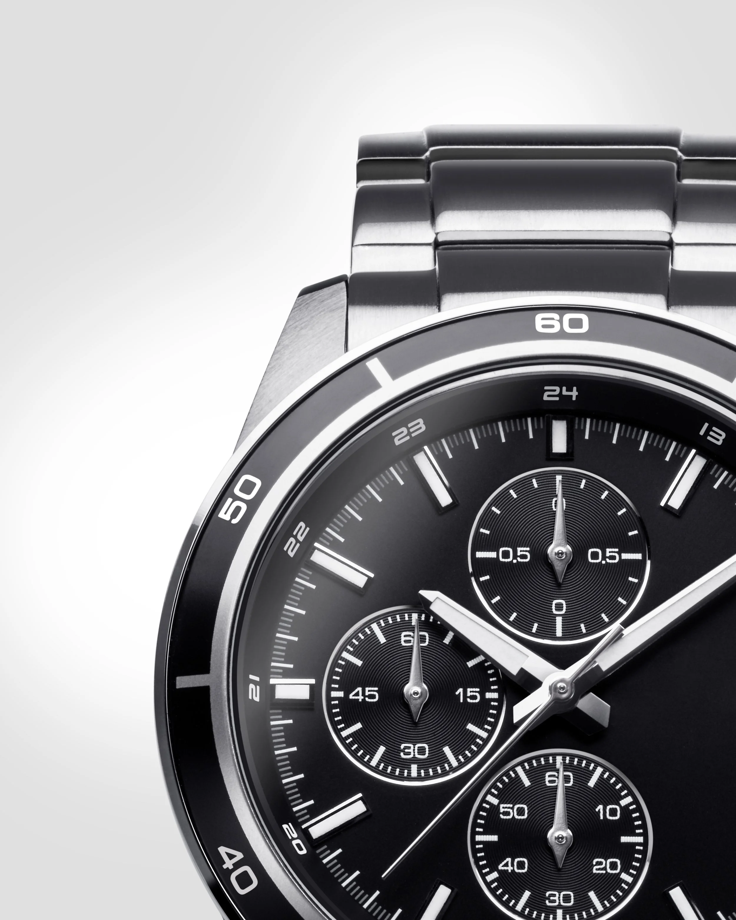 Close-up of a modern black and silver analog watch face with multiple dials and a stainless steel strap.