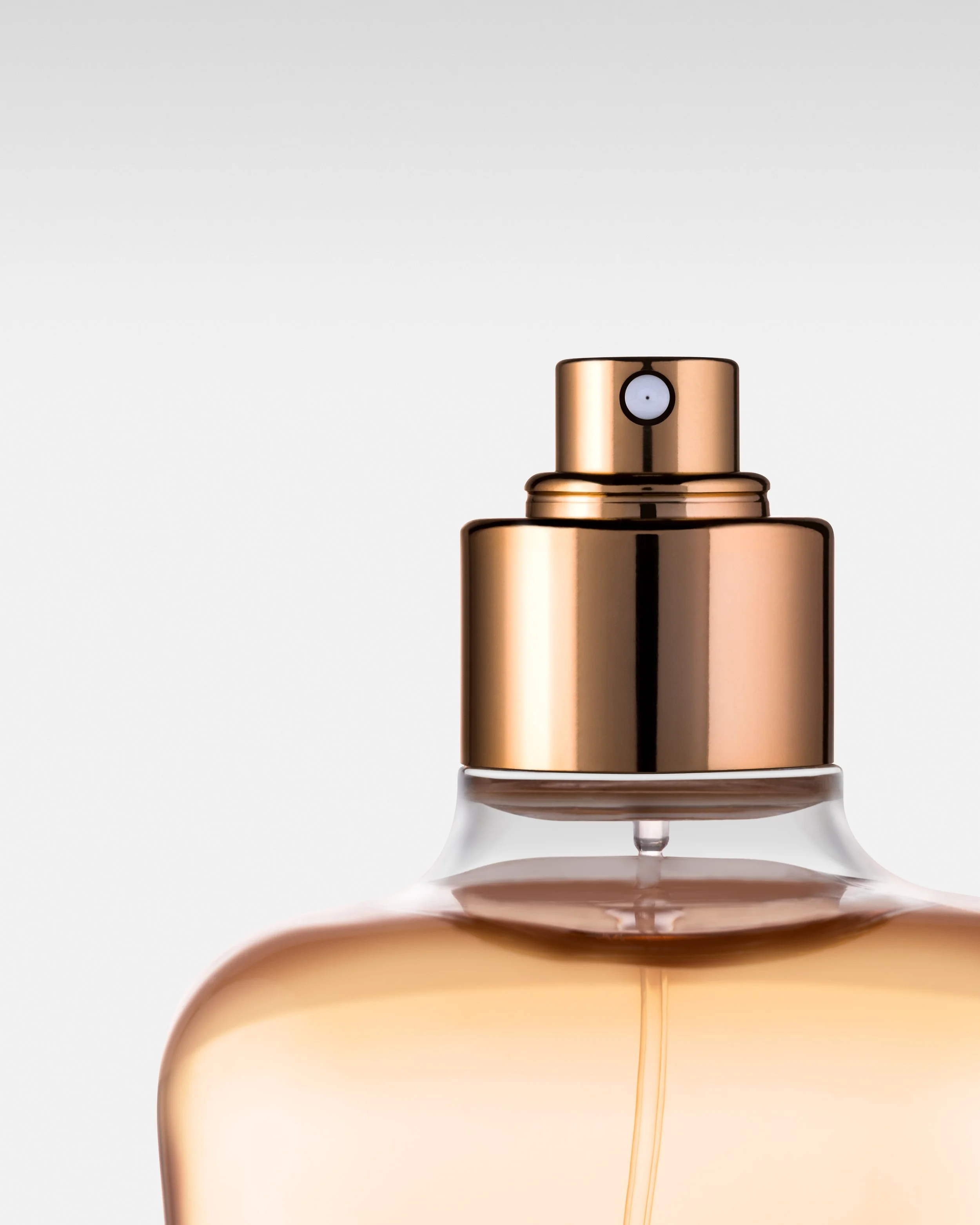Close-up of a metallic spray bottle nozzle with a white background.