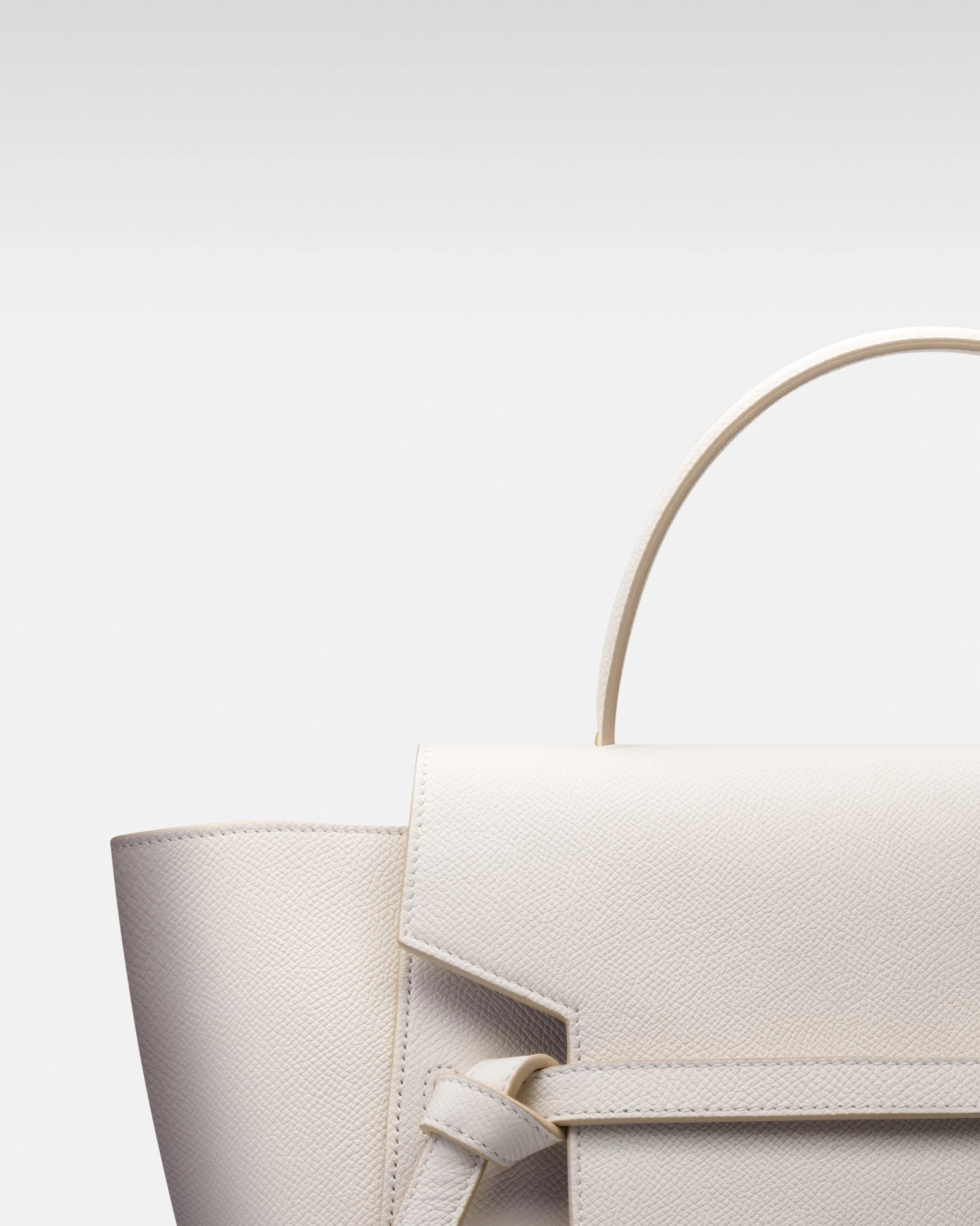 Close-up of a white leather handbag with textured surface and strap, against a plain light background.