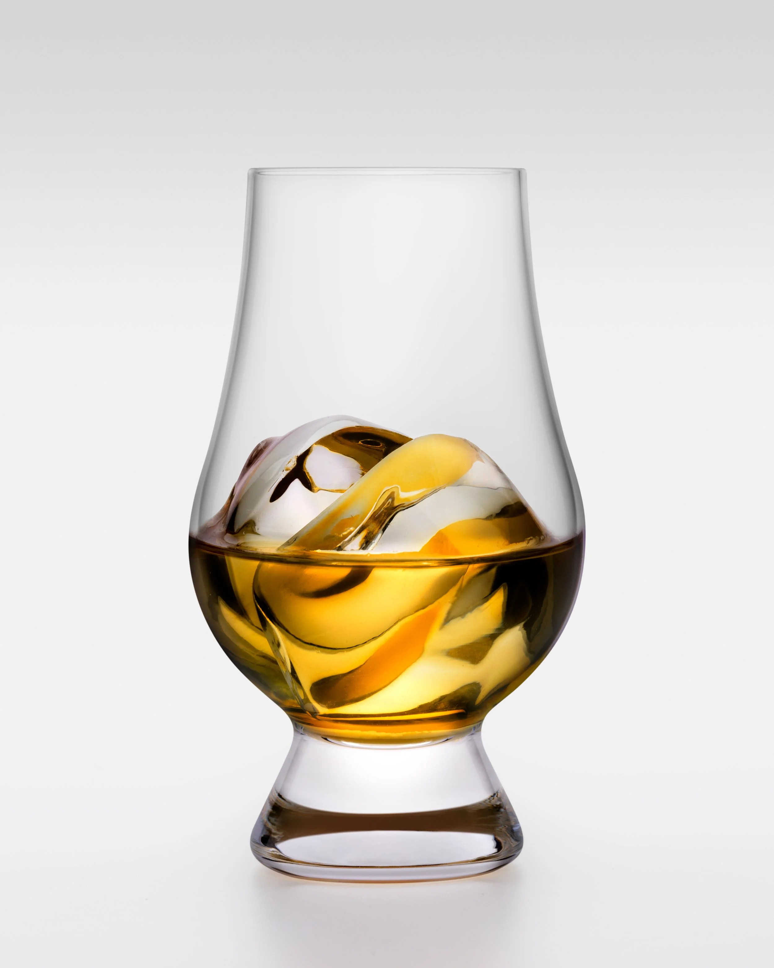 A clear glass vase with a wide base and narrow top, containing a swirl of white, yellow, and black marbled glass inside.