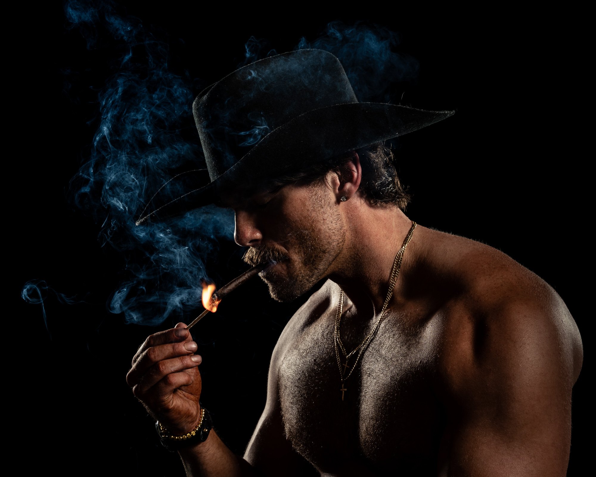 Shirtless man in cowboy hat with cigar