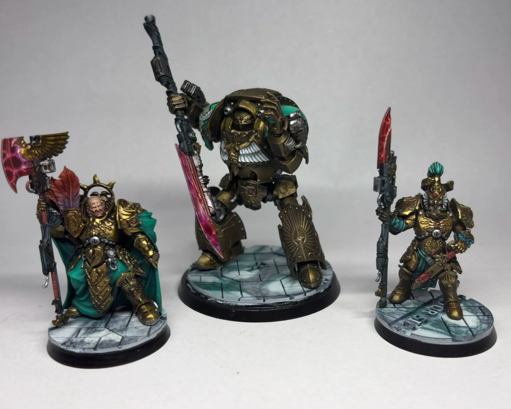 Detailed miniature model of a sci-fi armored warrior with a red cape, black and silver armor, holding a glowing green sword, standing on a rocky base with a flag bearing a skull and flames, in a dark setting.