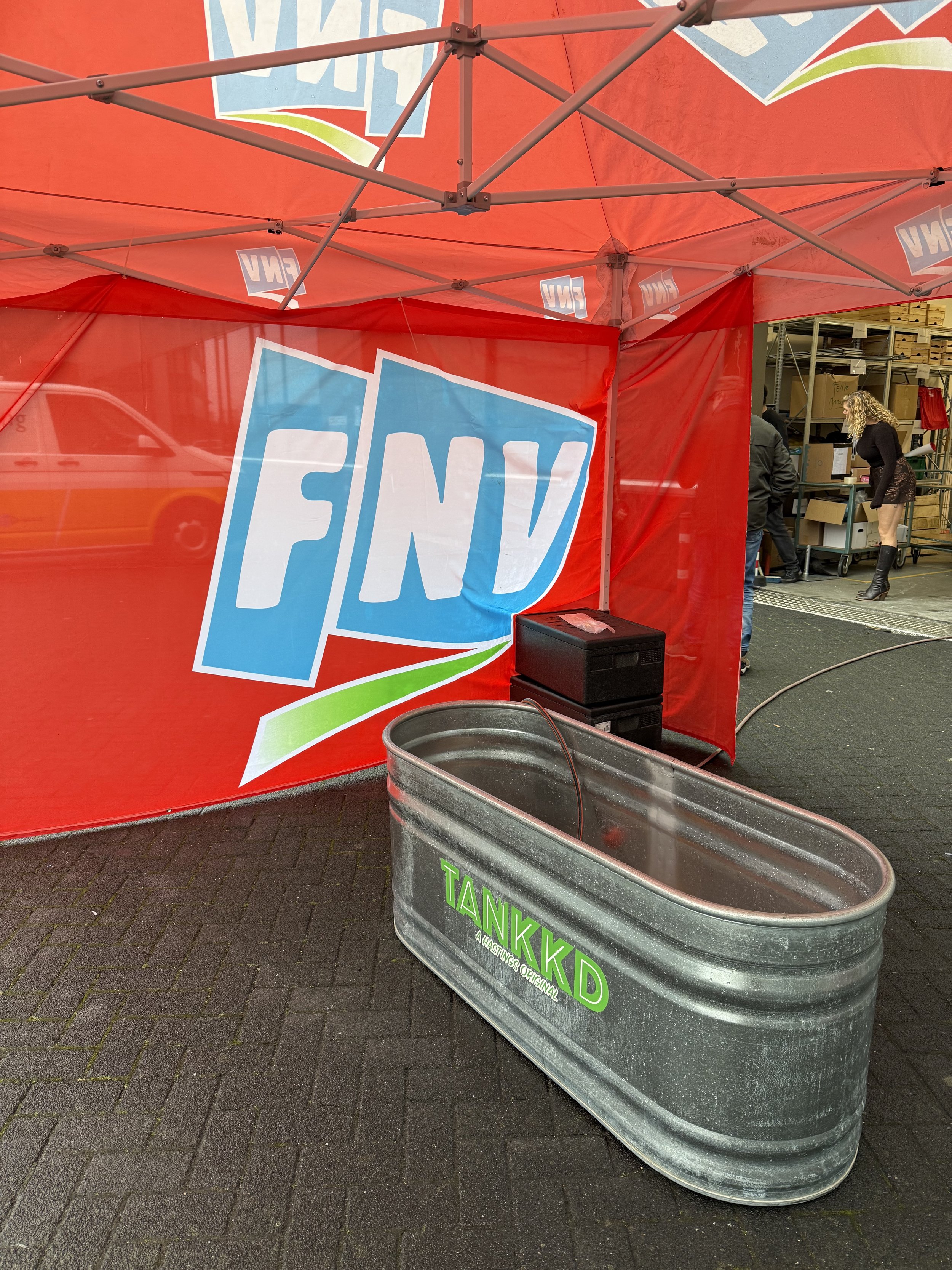 Een rode tent met het logo van FNVP en een metalen tankkist met groene tekst.