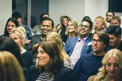 A diverse group of people sitting and smiling at a seminar or conference.