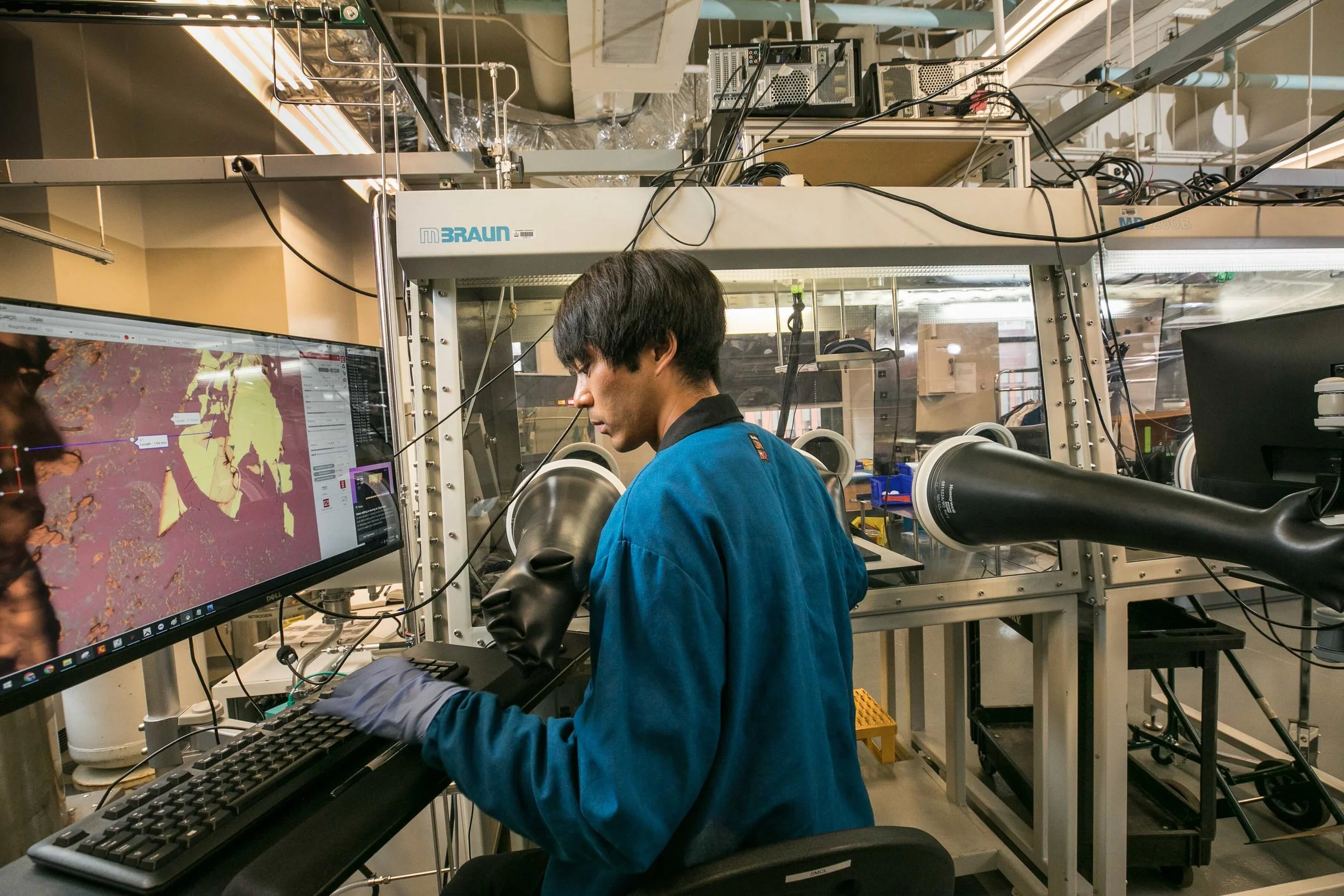 User inspecting 2D material samples using the autofinder inside a glovebox for controlled-environment handling.