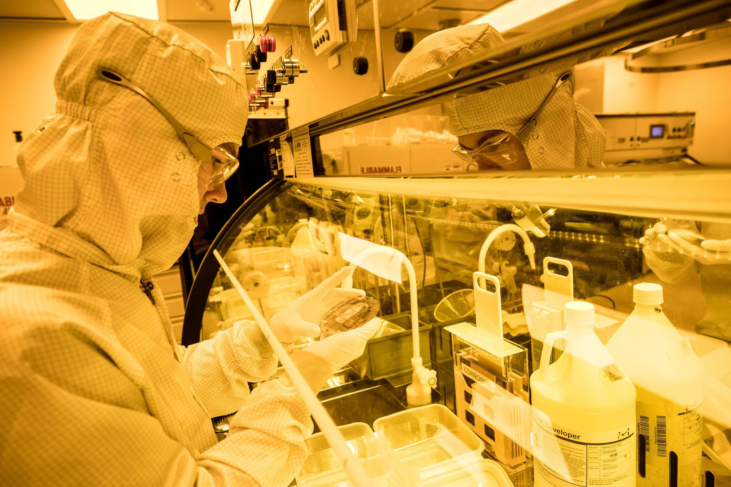 Cleanroom user inspecting a wafer at the solvent hood shortly after photolithography development.