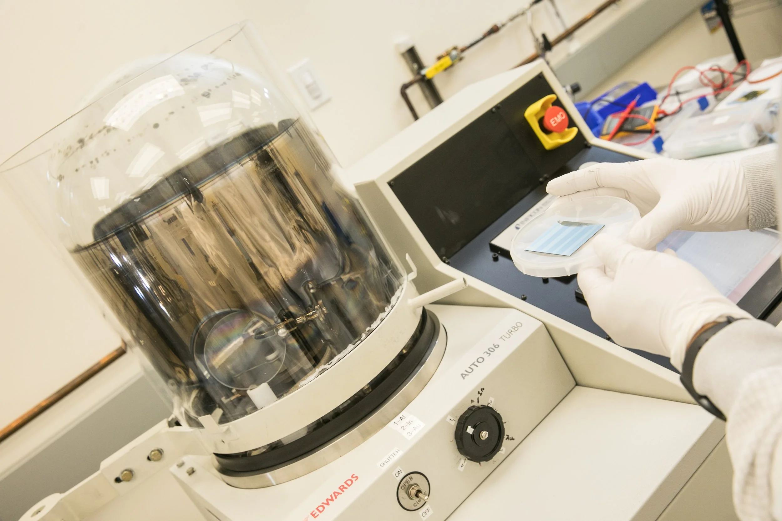 Cleanroom user inspecting a wafer before loading it into the thermal evaporator for thin-film metal deposition.