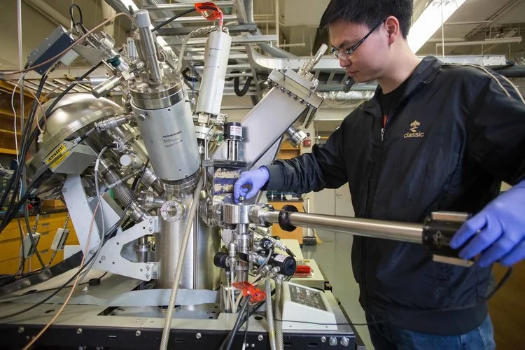 User operating the X-ray Photoelectron Spectroscopy (XPS) system in the Shared Materials Characterization Lab, preparing a sample for surface chemical analysis