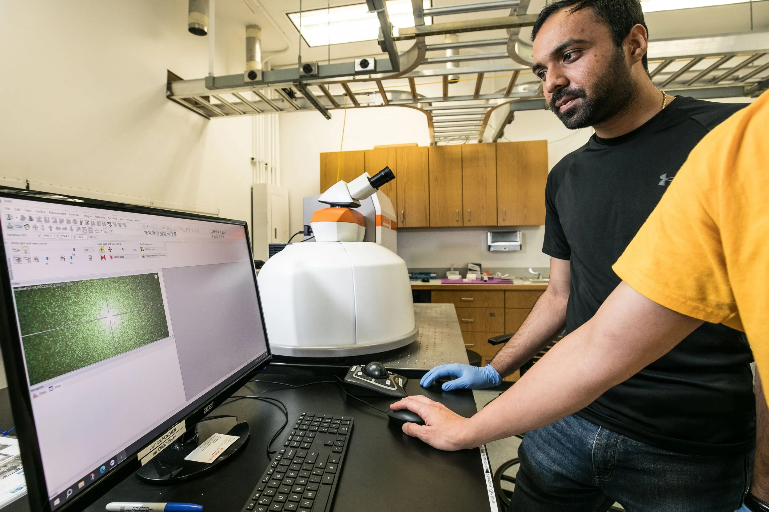 User receiving hands-on training on the Raman spectrometer in the Shared Materials Characterization Lab, learning to perform vibrational spectroscopy measurements.