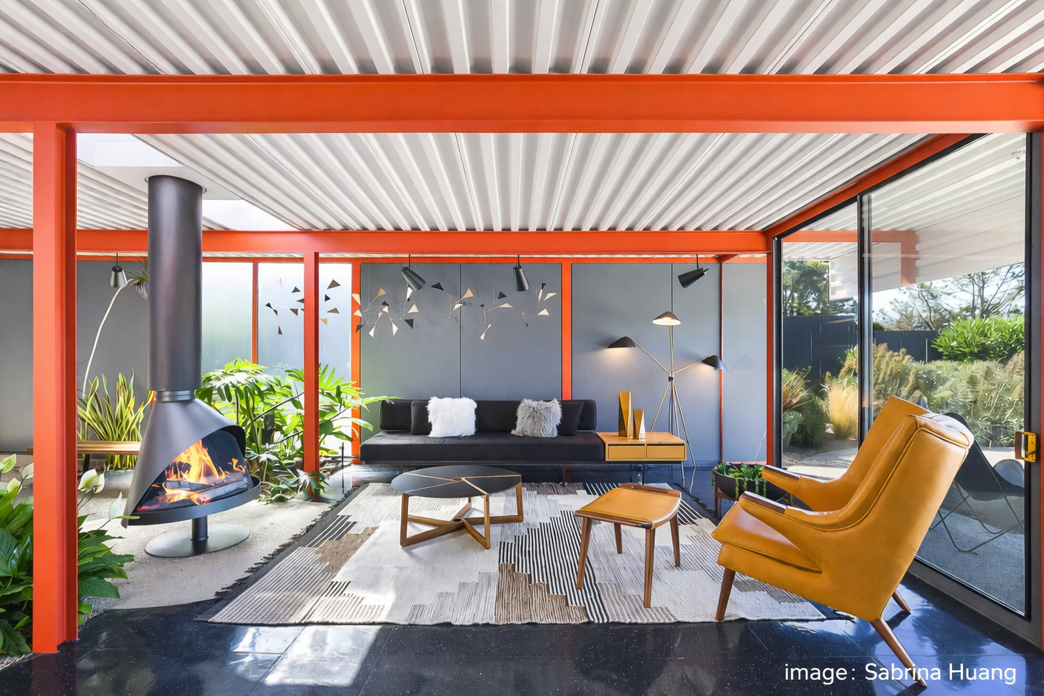 Orange steel beams and glass walls in the Eichler X-100 living room